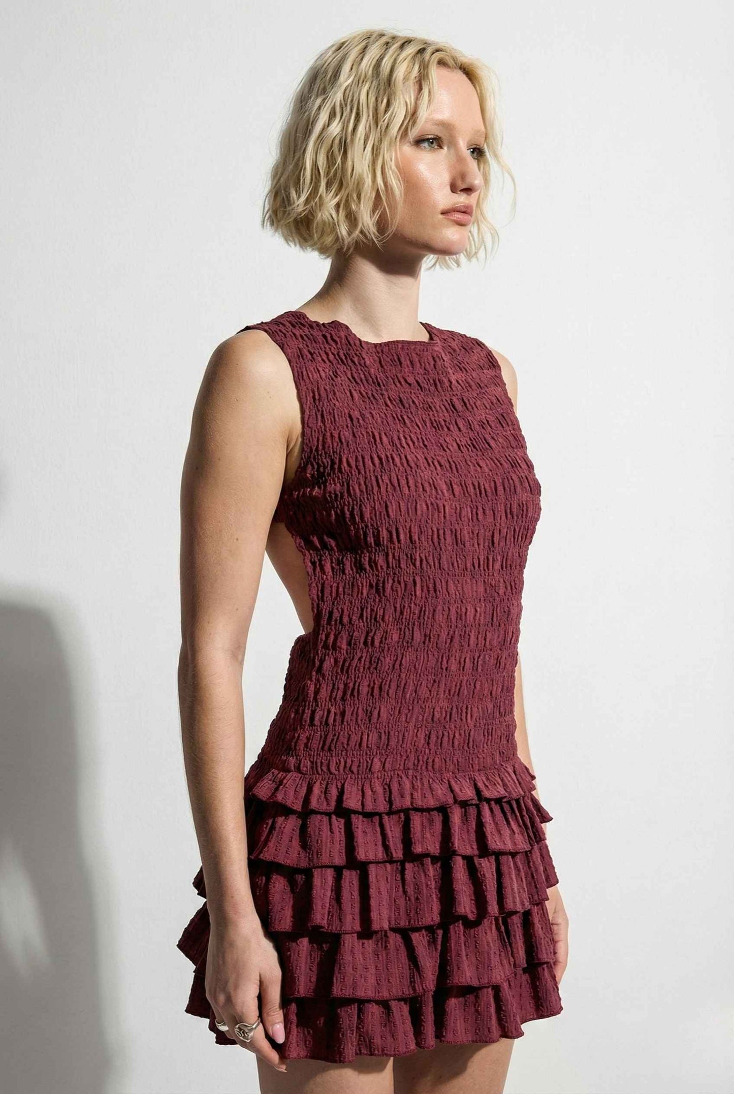 Woman wearing a Cleo Mini Wine Smocked Ruffle Sleeveless Dress against a white background