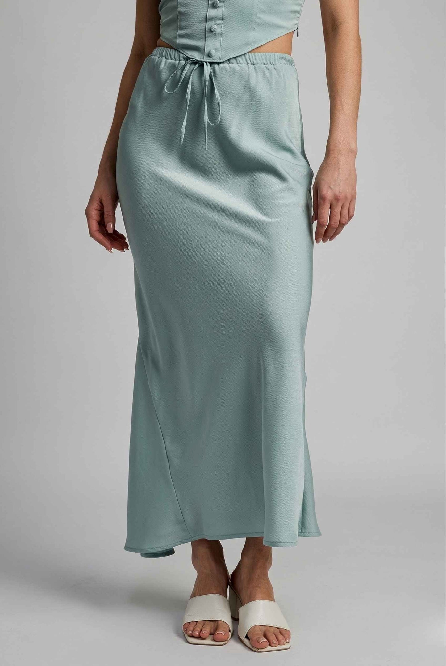 Woman wearing a Cleo Skirt Light Blue Satin Drawstring Maxi Skirt on a plain background