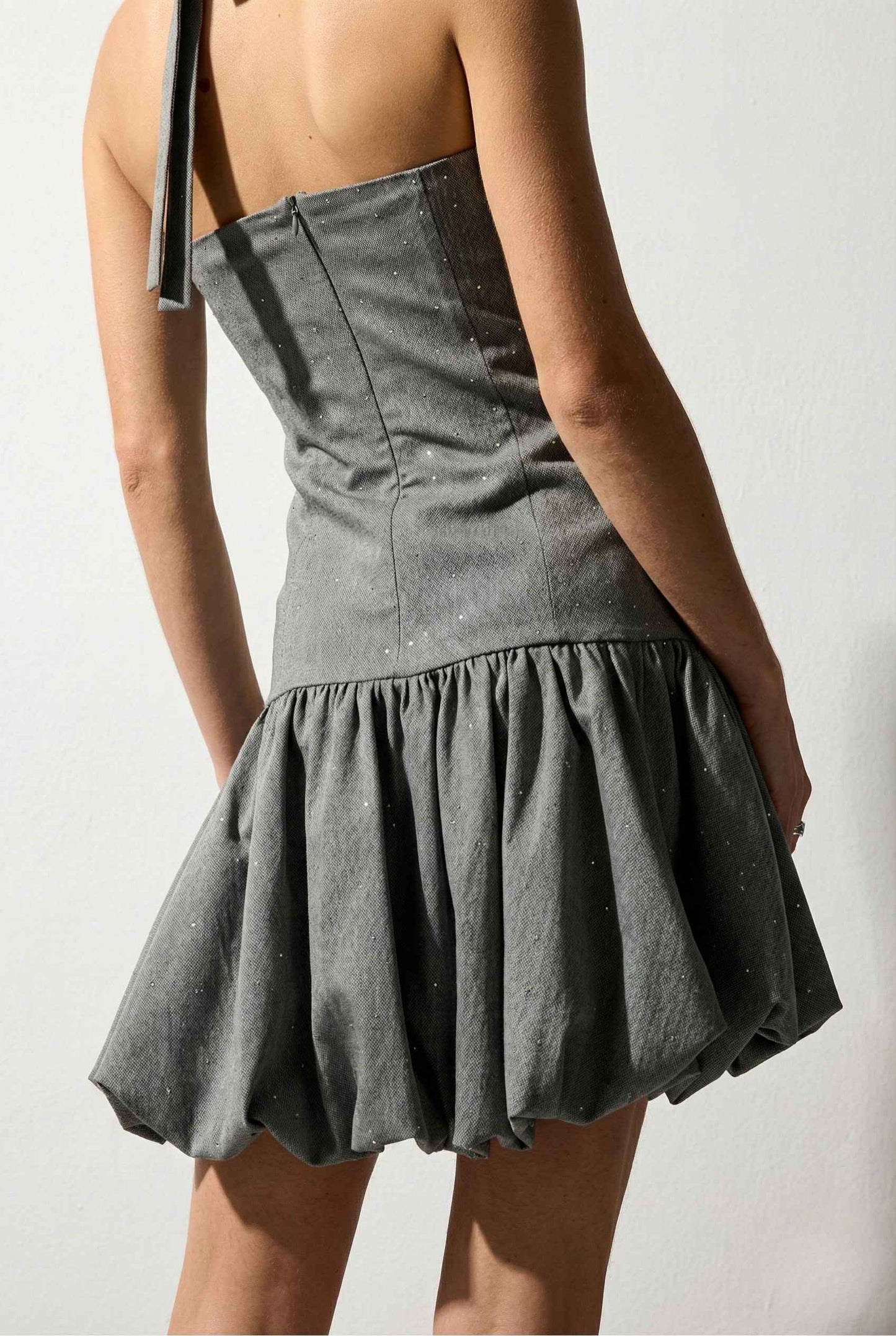 Person wearing a Colette Mini Grey Rhinestone Drop-Waist Bubble Dress with a plain background
