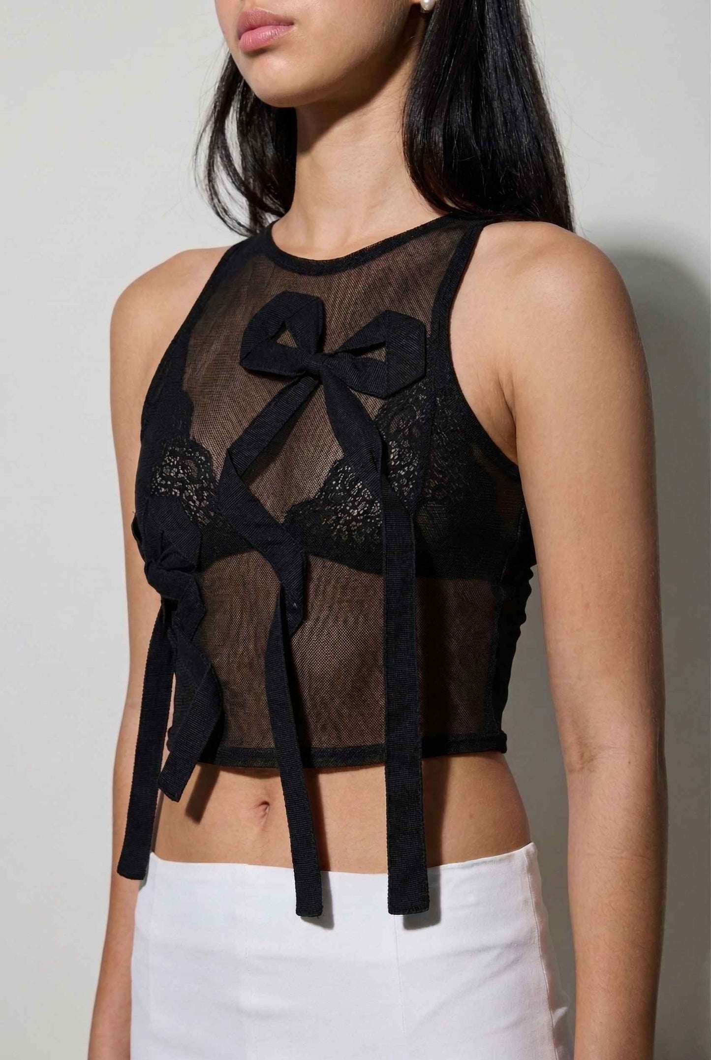 Colette Top Black Sheer Mesh Ribbon Bow Tank with bow details worn by a person against a plain background