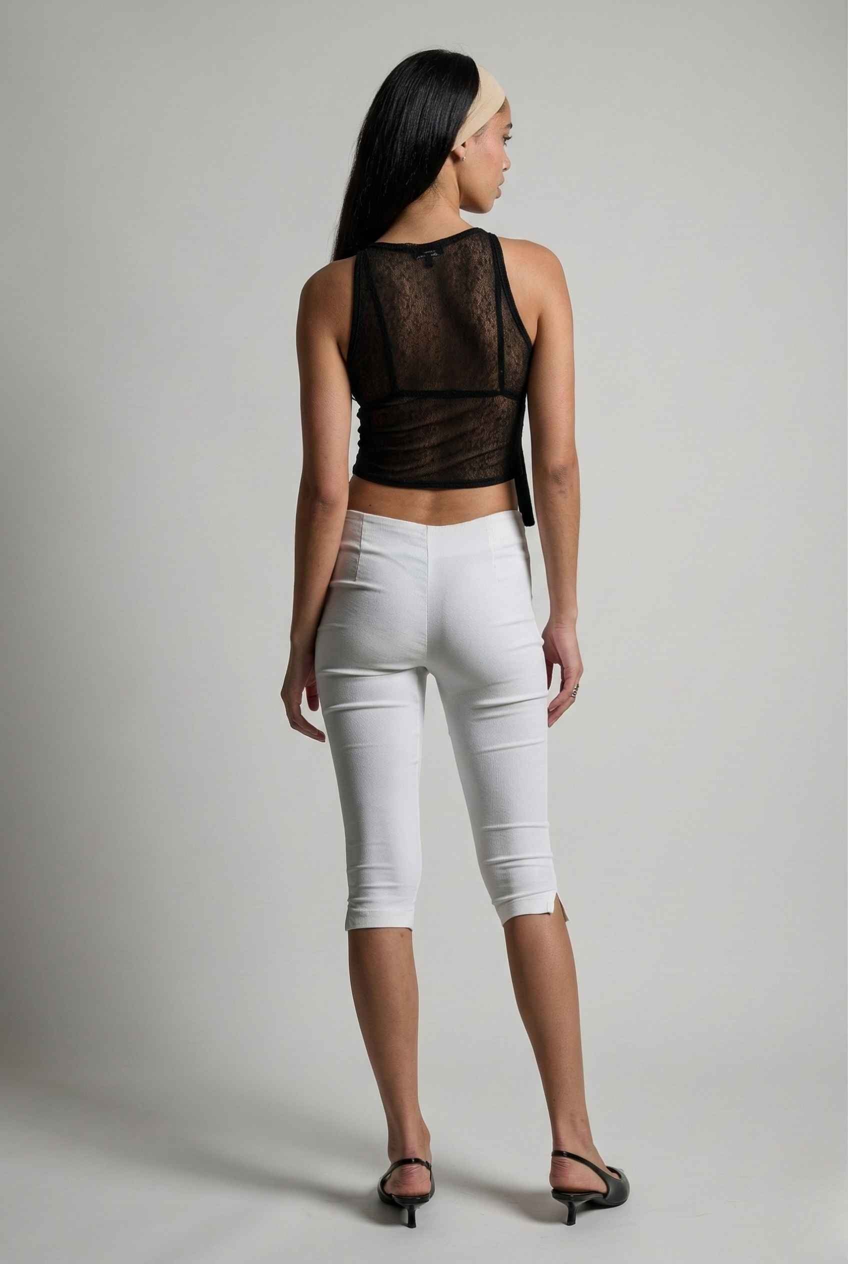 Woman wearing a Colette Top Black Sheer Mesh Ribbon Bow Tank and pants on a plain background
