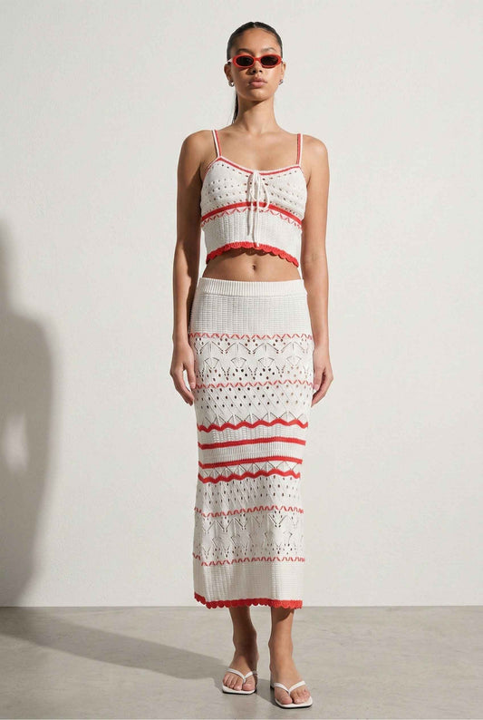 Model wearing Coralie Skirt in White Scalloped Stripe Crochet Knit Maxi with matching crop tank and heeled sandals on a plain background