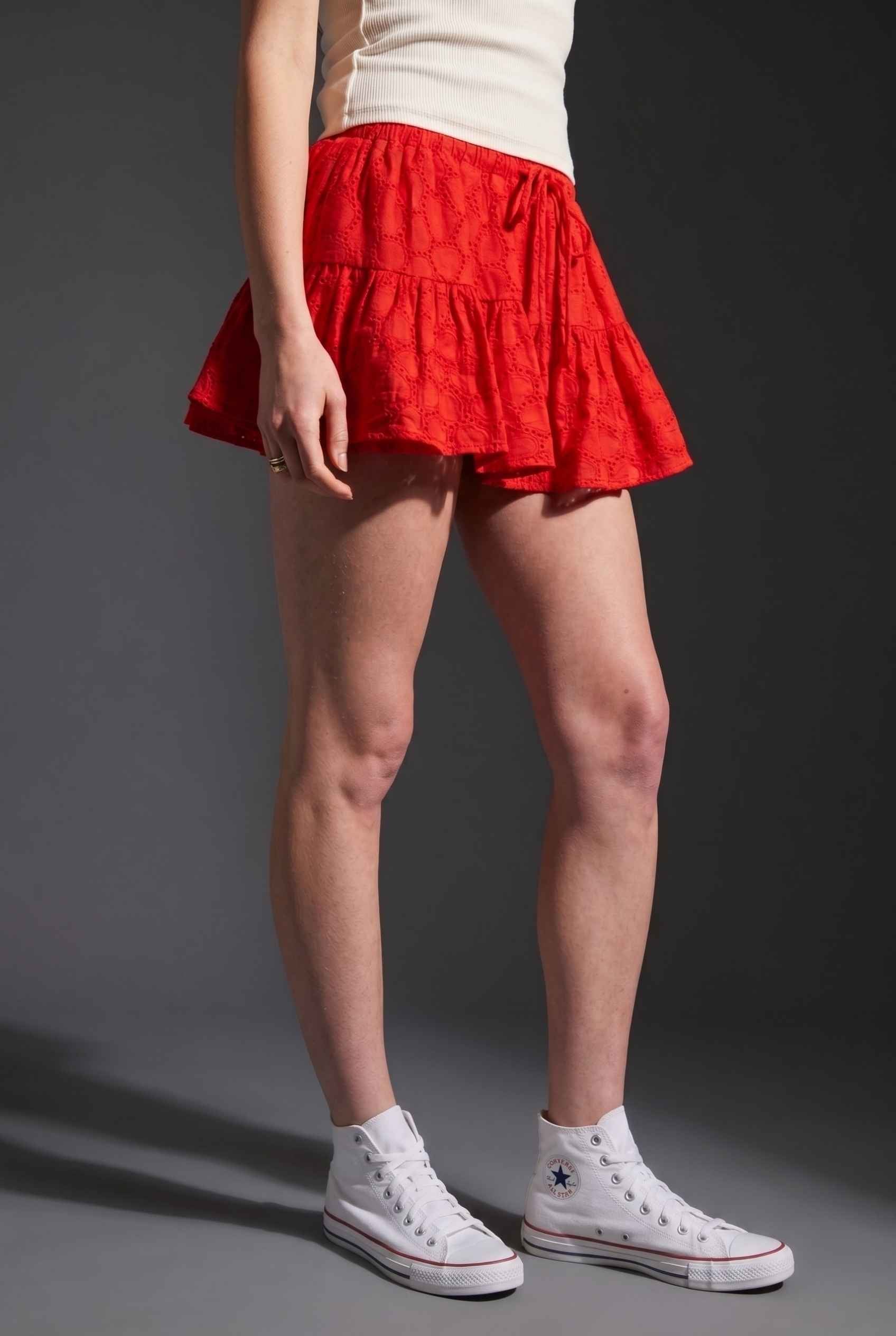 Model wearing Corinne Tiered Cotton Skort Pleated Ruffle Mini Skort in Red paired with tank top and sneakers