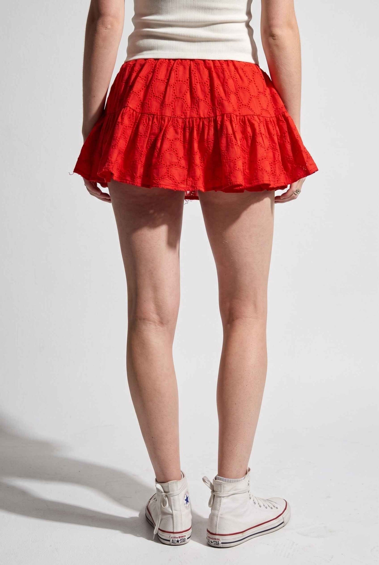 Model wearing Corinne Tiered Cotton Skort Pleated Ruffle Mini Skort in Red paired with tank top and sneakers