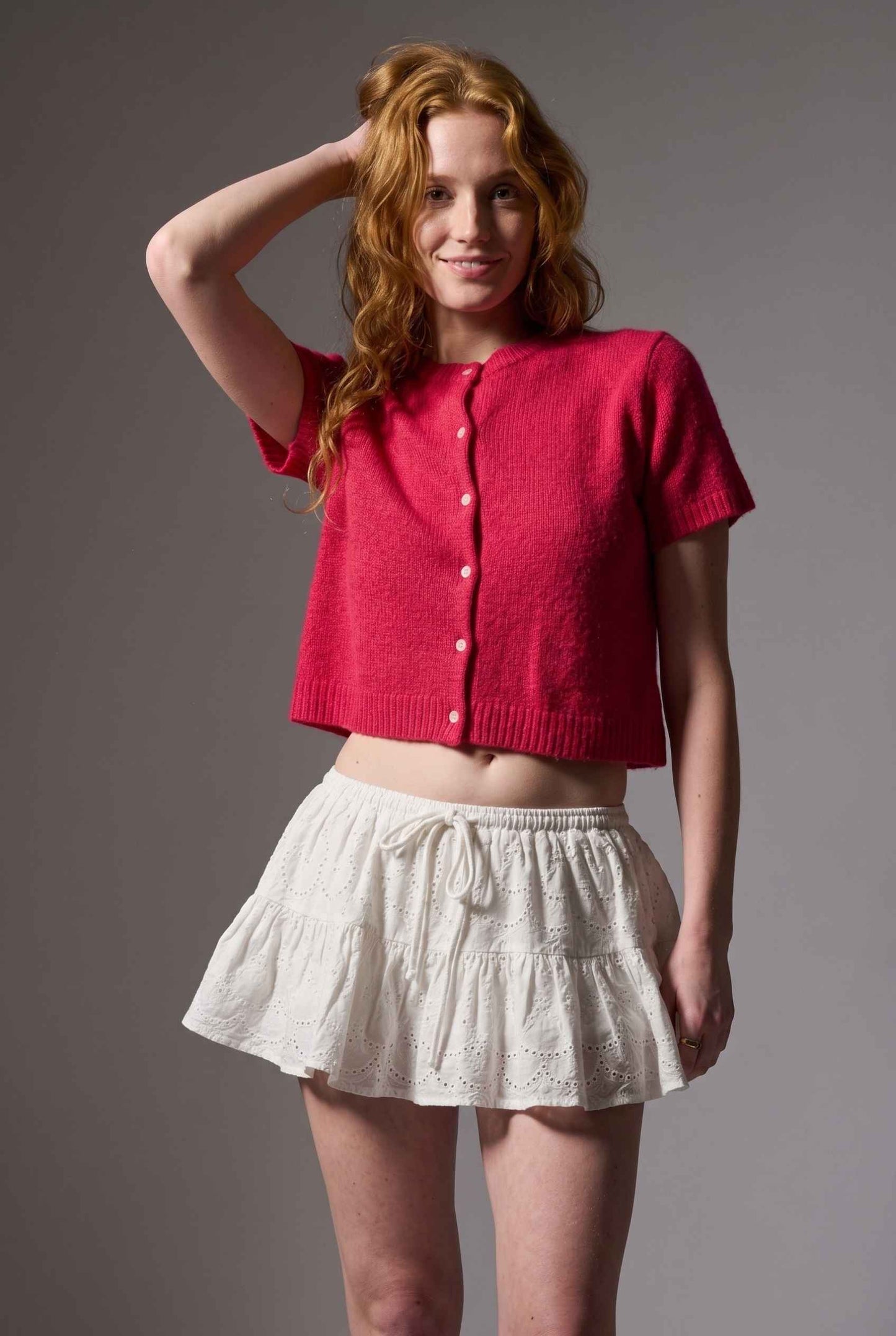 Model wearing Corinne Cotton Skort Pleated Ruffle Mini Skort in White with cropped short sleeve cardigan