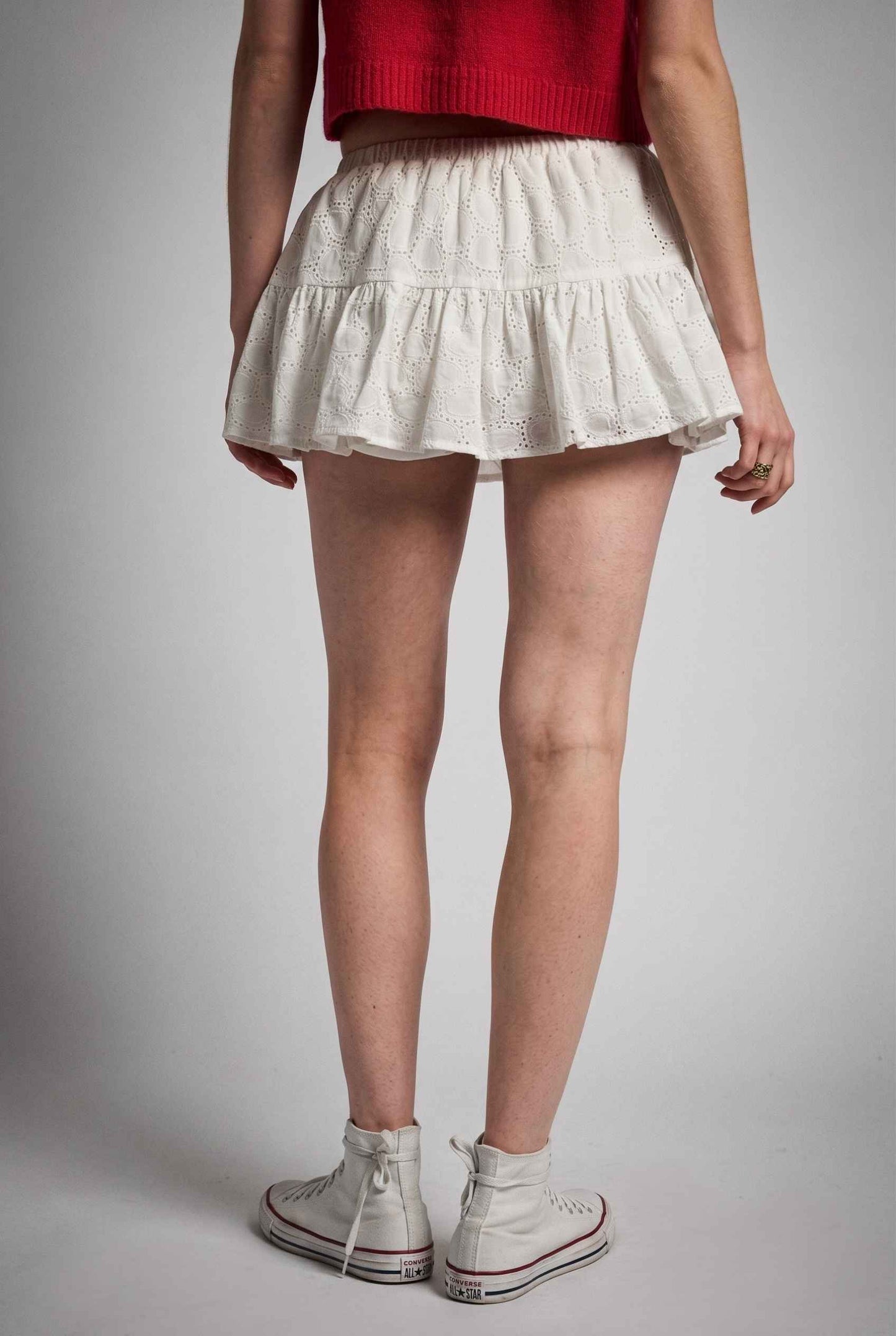 Model wearing Corinne  Cotton Skort Pleated Ruffle Mini Skort in White with cropped short sleeve cardigan and sneakers