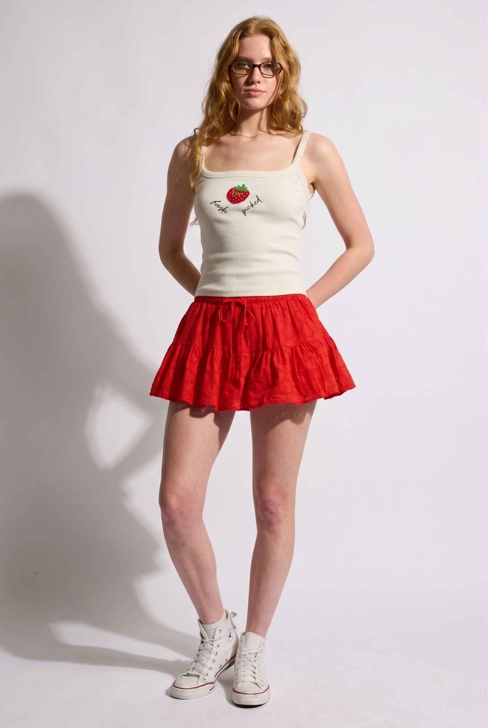Model wearing Corinne Tiered Cotton Skort Pleated Ruffle Mini Skort in Red paired with tank top and sneakers