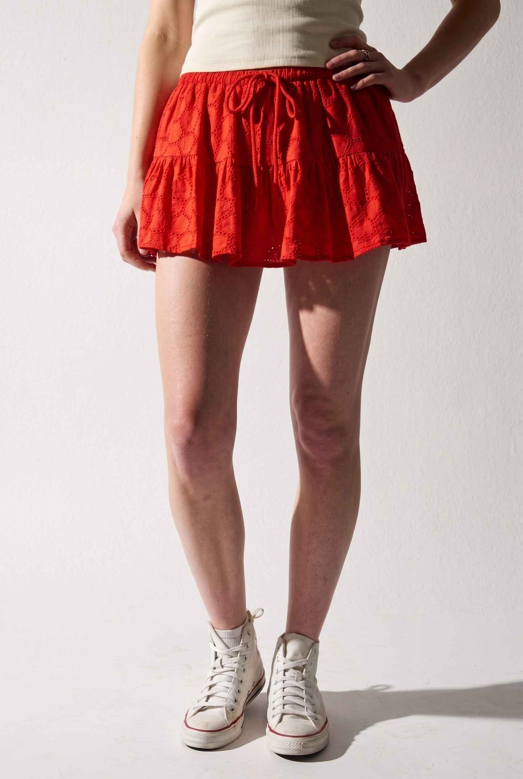 Model wearing Corinne Tiered Cotton Skort Pleated Ruffle Mini Skort in Red paired with tank top and sneakers
