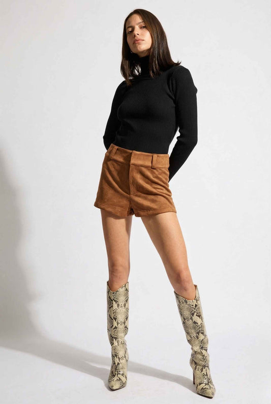Woman wearing a black turtleneck, Dakota Shorts Brown Faux Suede Low-Rise Mini Shorts, and patterned boots on a white background