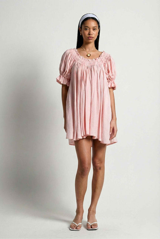 Woman wearing a Daphne Mini Pink Puff Sleeve Babydoll Dress against a white background