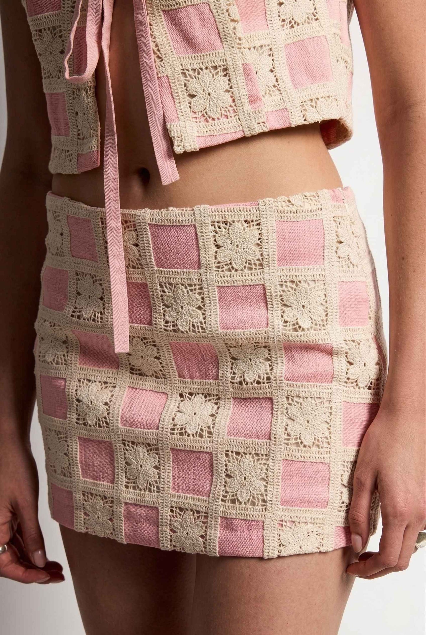 Model wearing Daphne Skirt in Pink Modern Jacquard Checkerboard Mini Skirt with matching vest top close up crochet detail