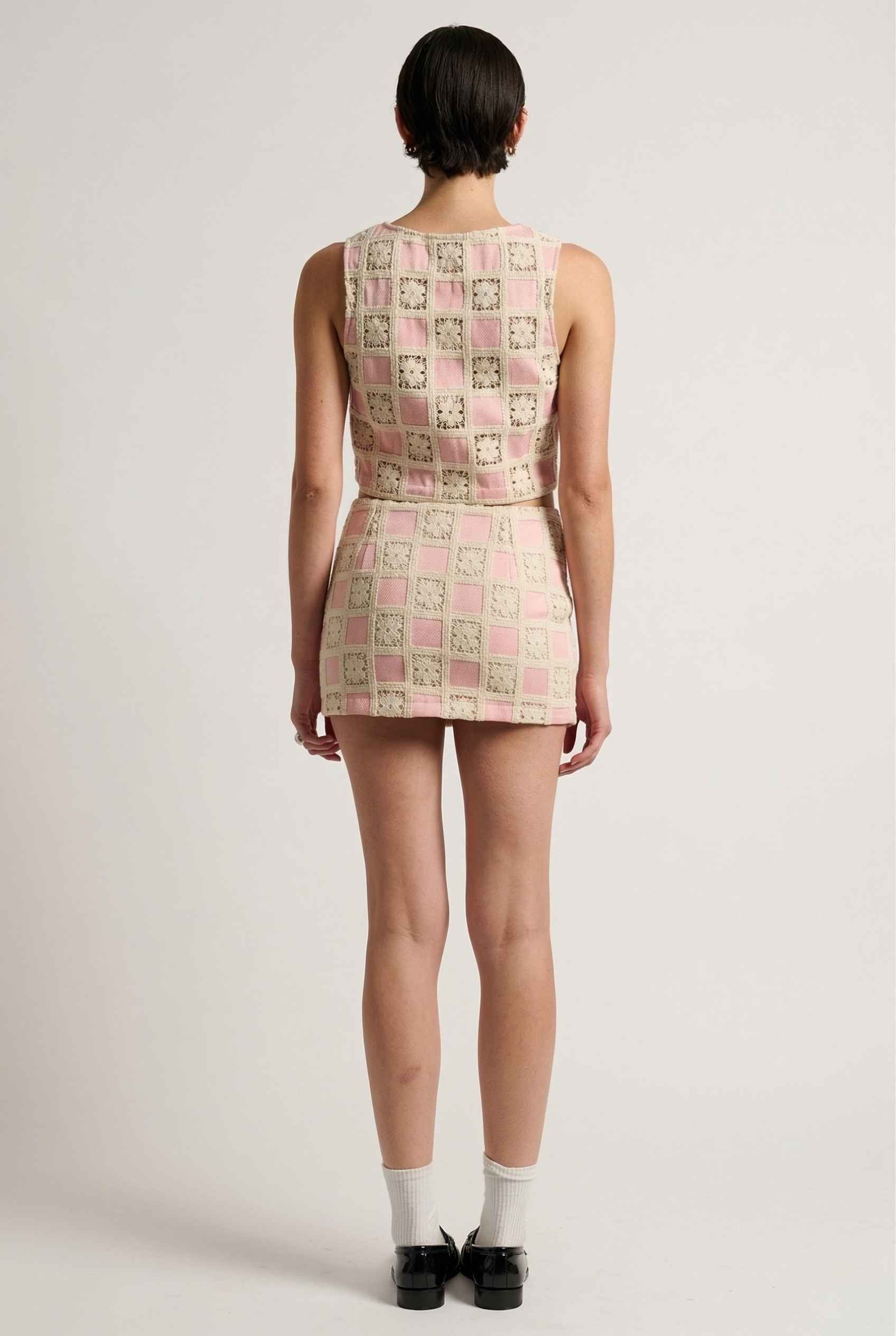 Model wearing Daphne Skirt in Pink Modern Jacquard Checkerboard Mini Skirt with matching vest top and shiny loafers with tall socks