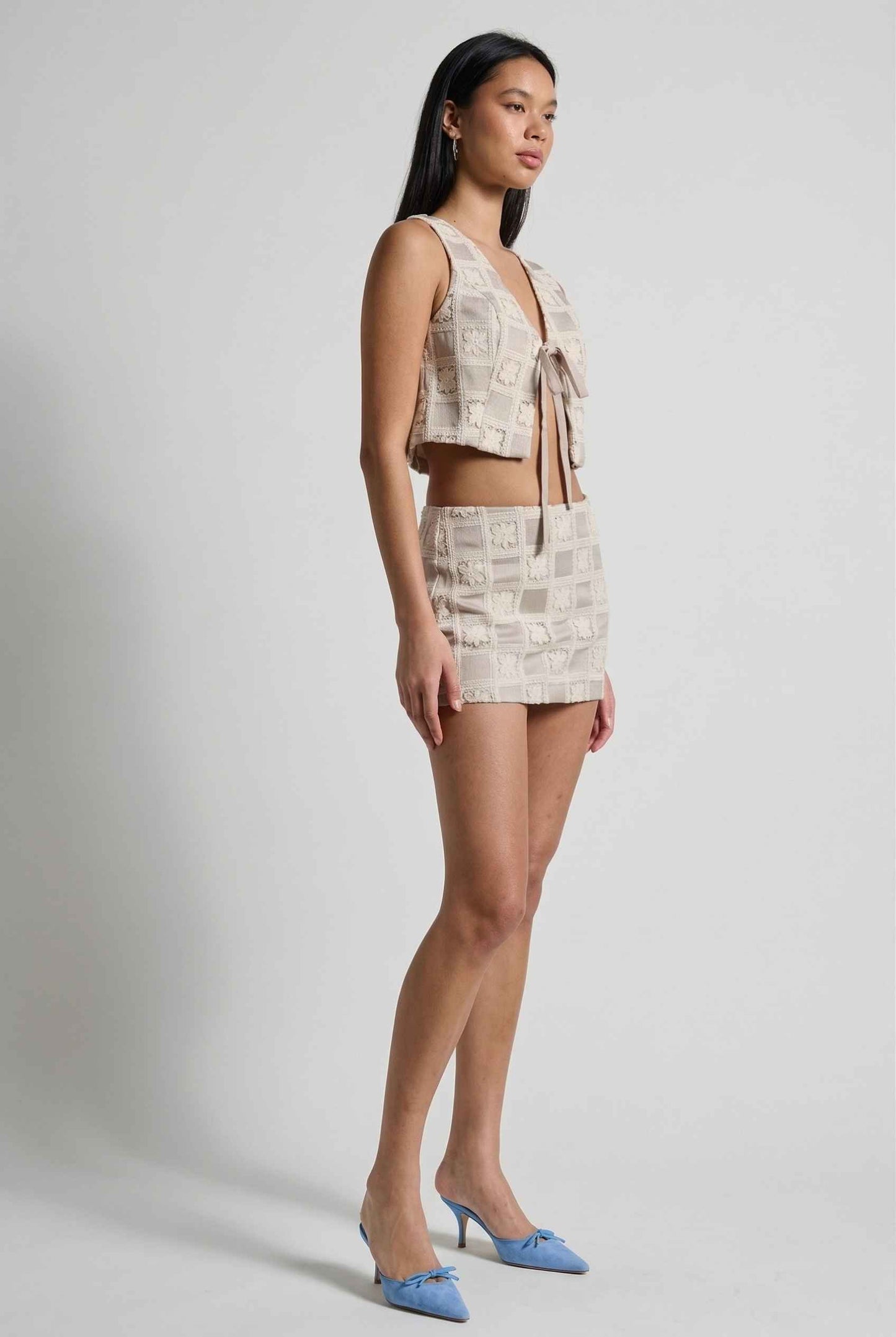 Model wearing Daphne Skirt in Natural Modern Jacquard Checkerboard Mini Skirt with matching vest top and heels