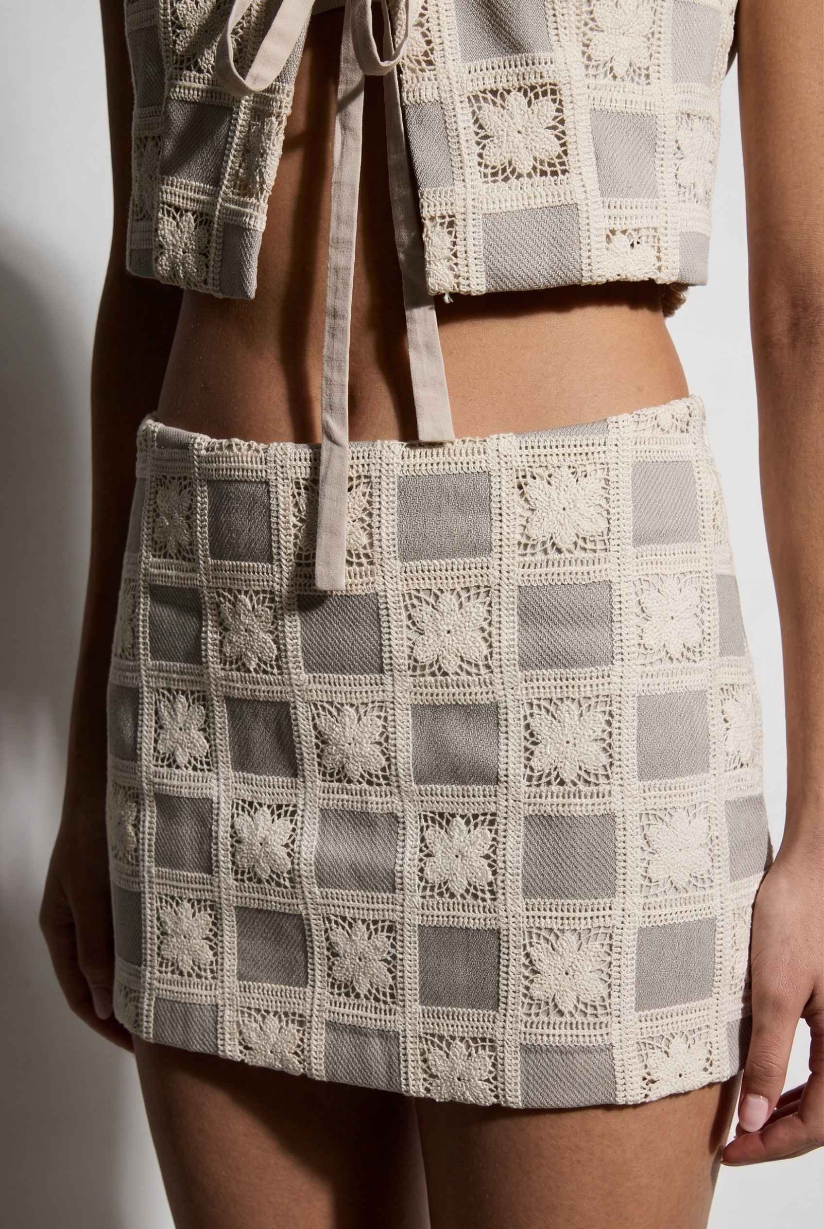 Model wearing Daphne Skirt in Natural Modern Jacquard Checkerboard Mini Skirt with matching vest top close up crochet detail