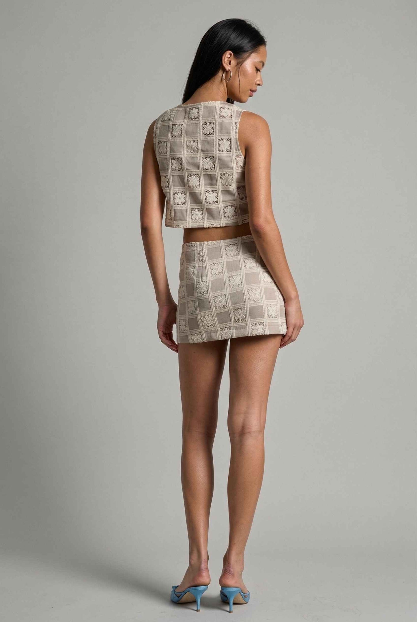 Model wearing Daphne Skirt in Natural Modern Jacquard Checkerboard Mini Skirt with matching vest top and heels