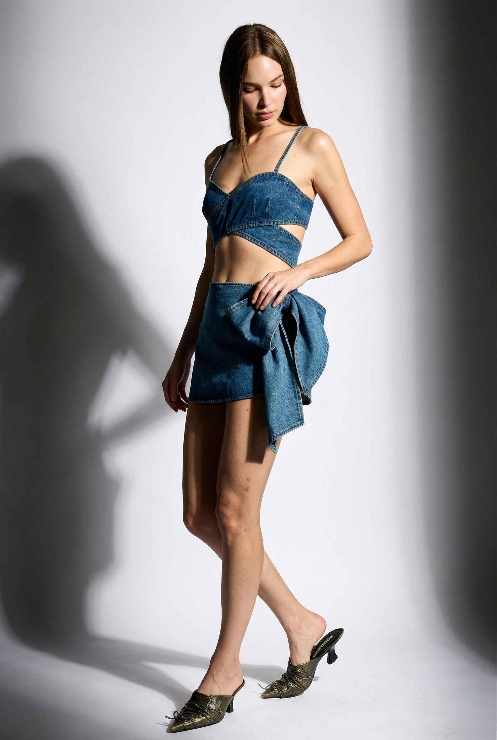 Model wearing Darcy Skirt in Medium Wash Cotton Denim Mini Skirt with Bow paired with matching bra top and pointed heels