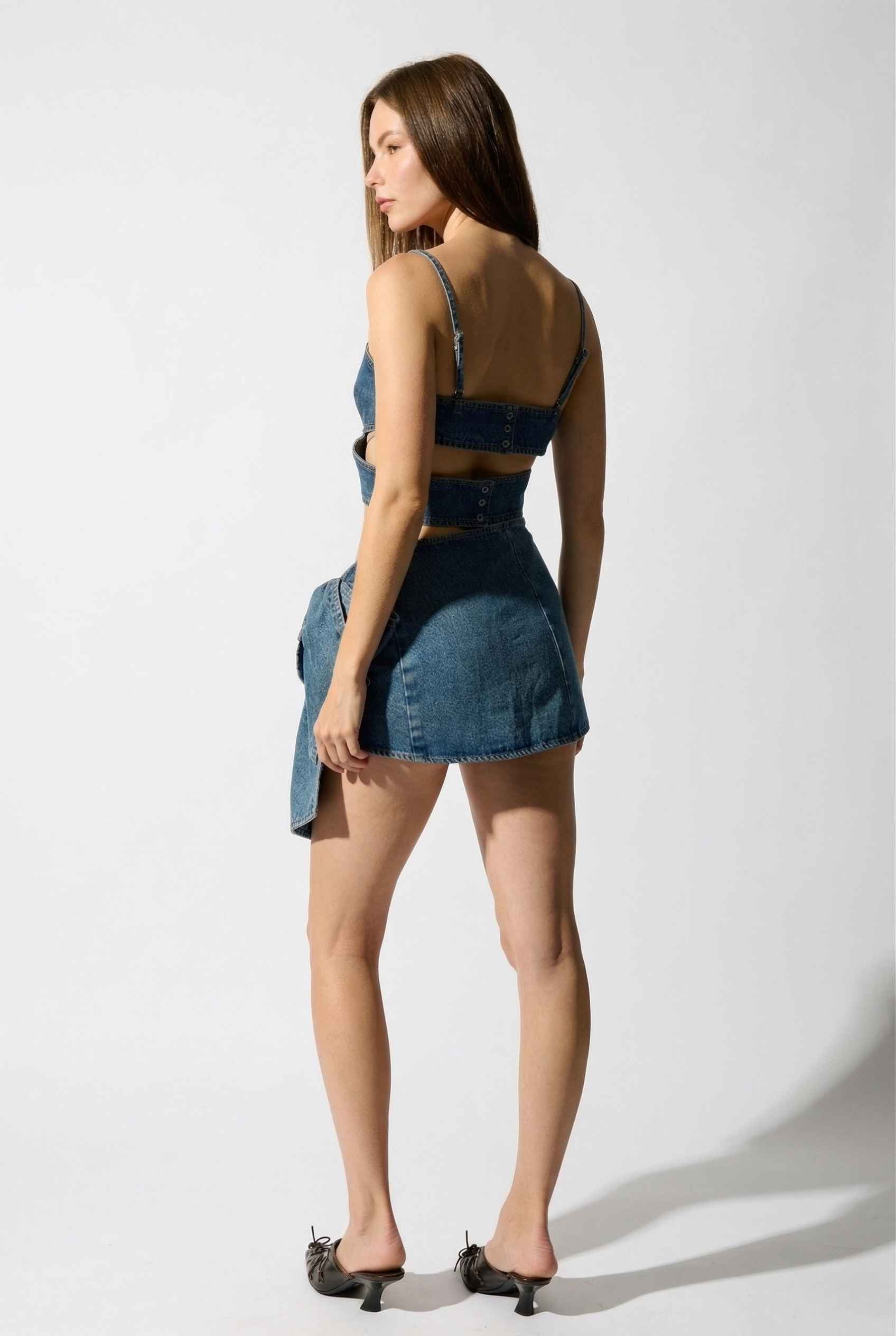 Model wearing Darcy Skirt in Medium Wash Cotton Denim Mini Skirt with Bow paired with matching bra top and pointed heels