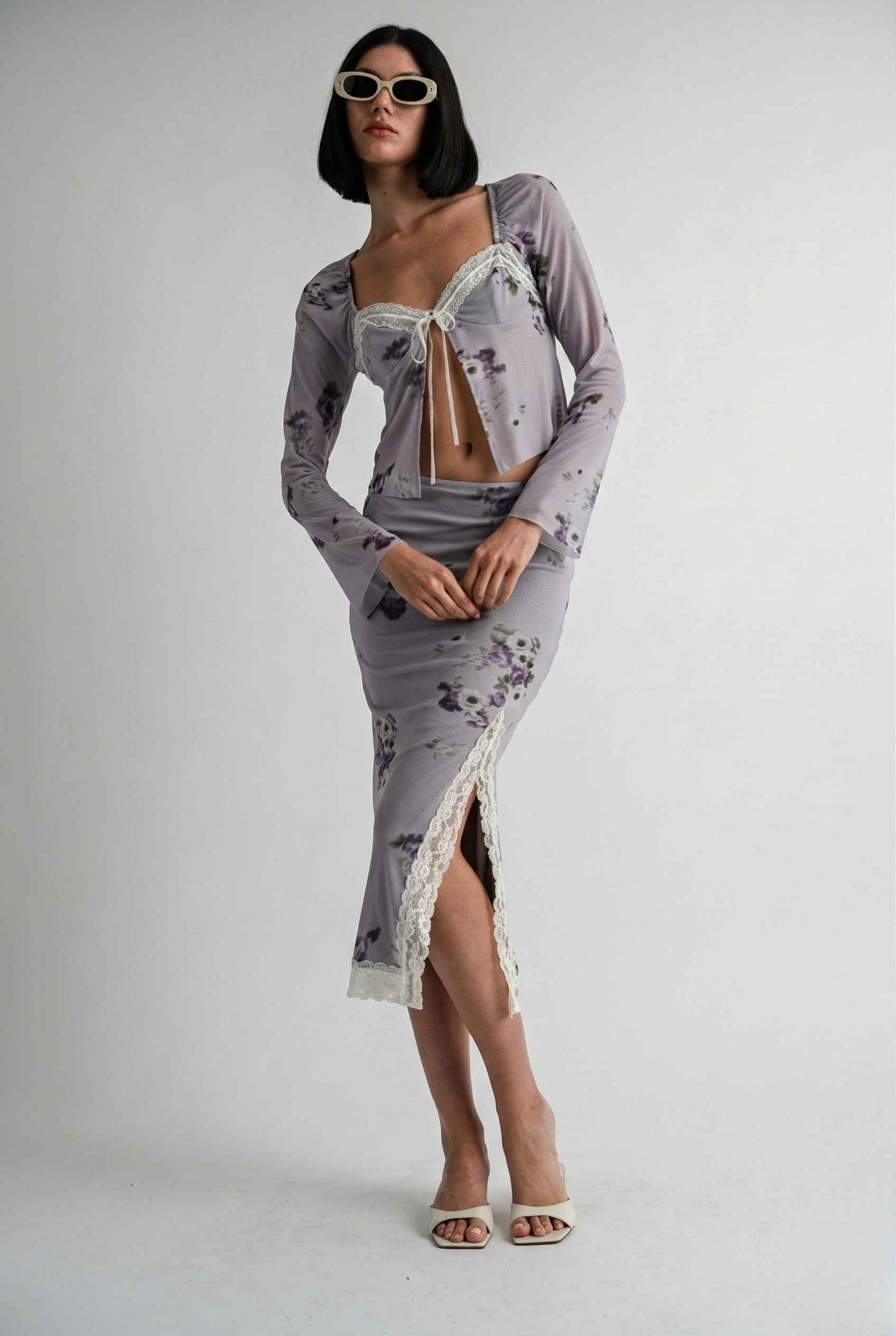 Woman wearing a Elara Top Lavender Floral Lace Trim Fly-Away Cardigan with a sheer overlay on a white background