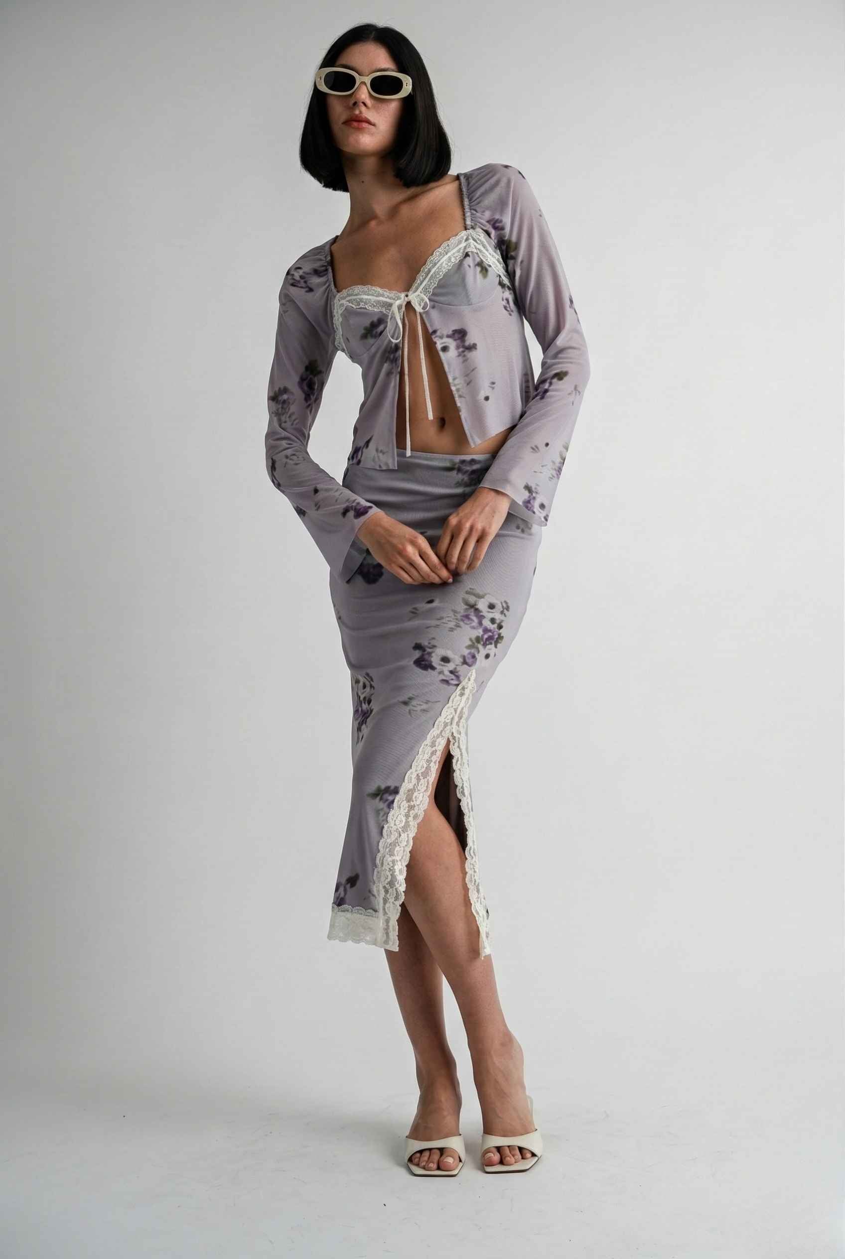 Woman wearing a Elara Top Lavender Floral Lace Trim Fly-Away Cardigan with a sheer overlay on a white background