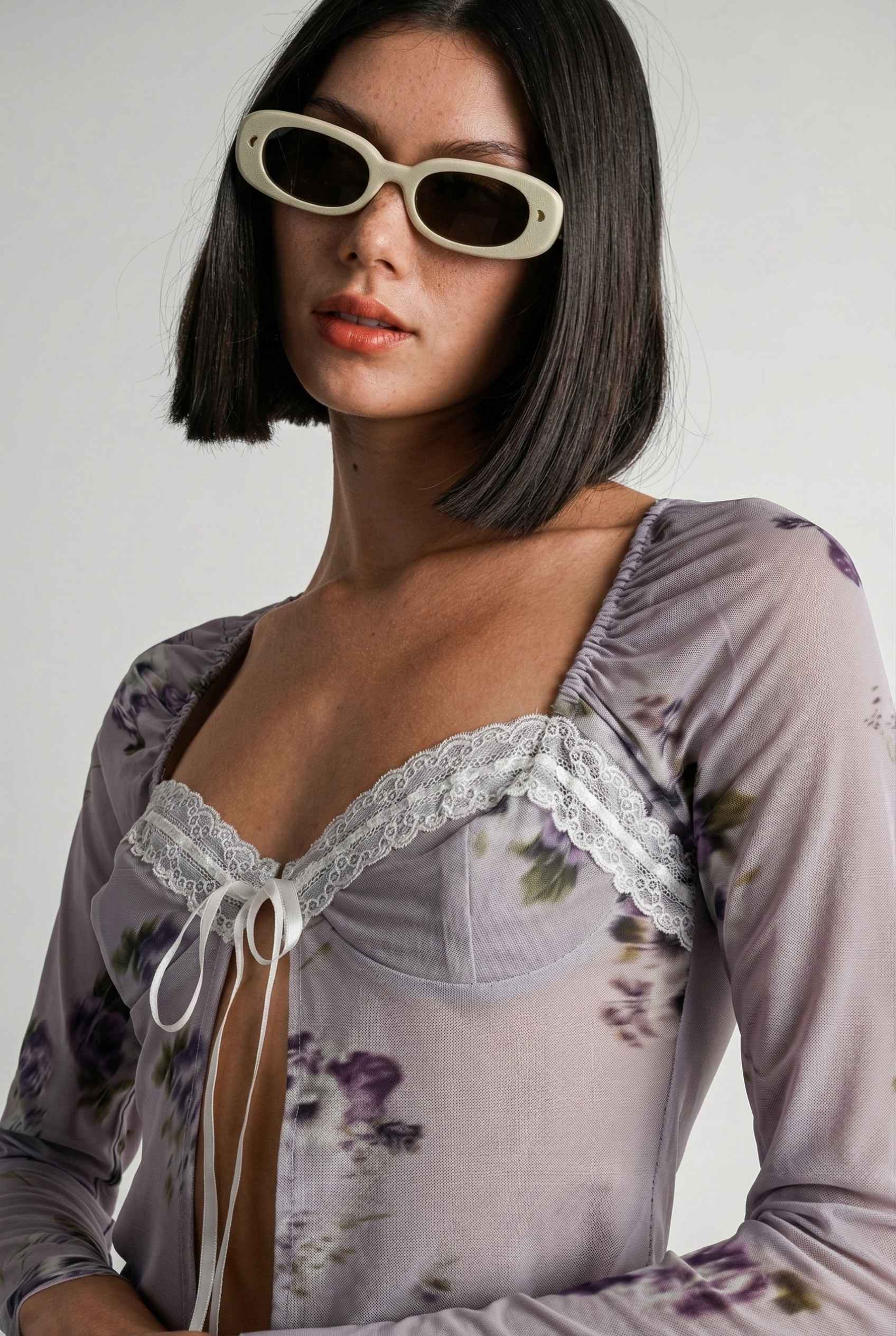 Woman wearing a Elara Top Lavender Floral Lace Trim Fly-Away Cardigan with lace details and sunglasses against a plain background