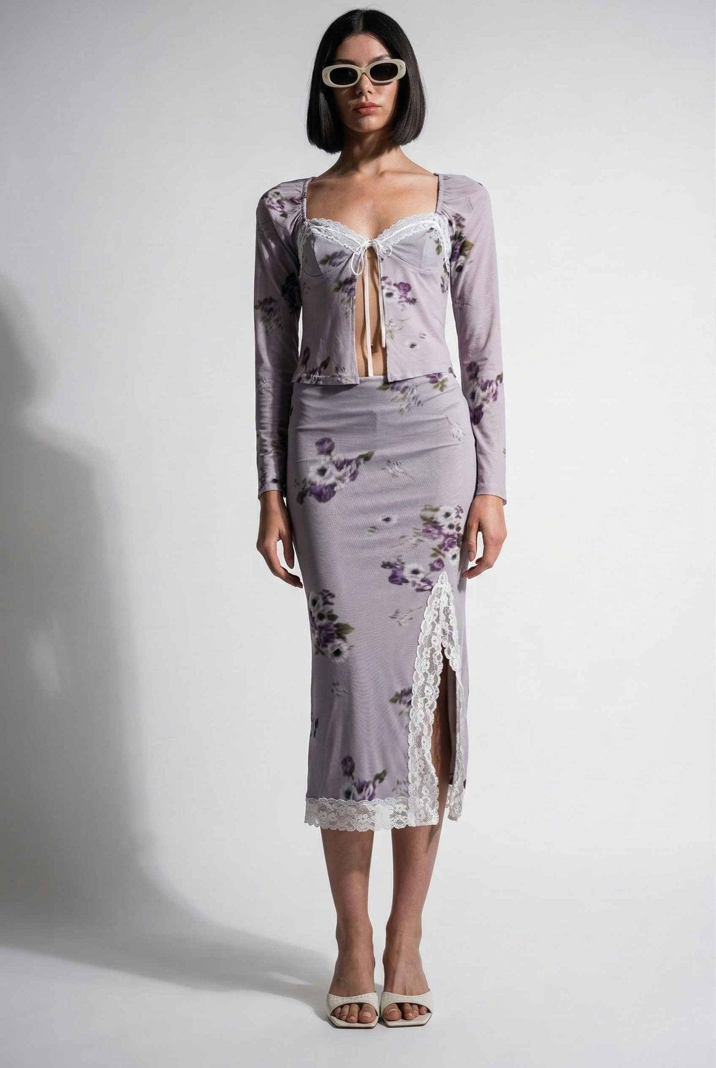 Woman wearing a Elara Top Lavender Floral Lace Trim Fly-Away Cardigan with a sheer overlay against a white background