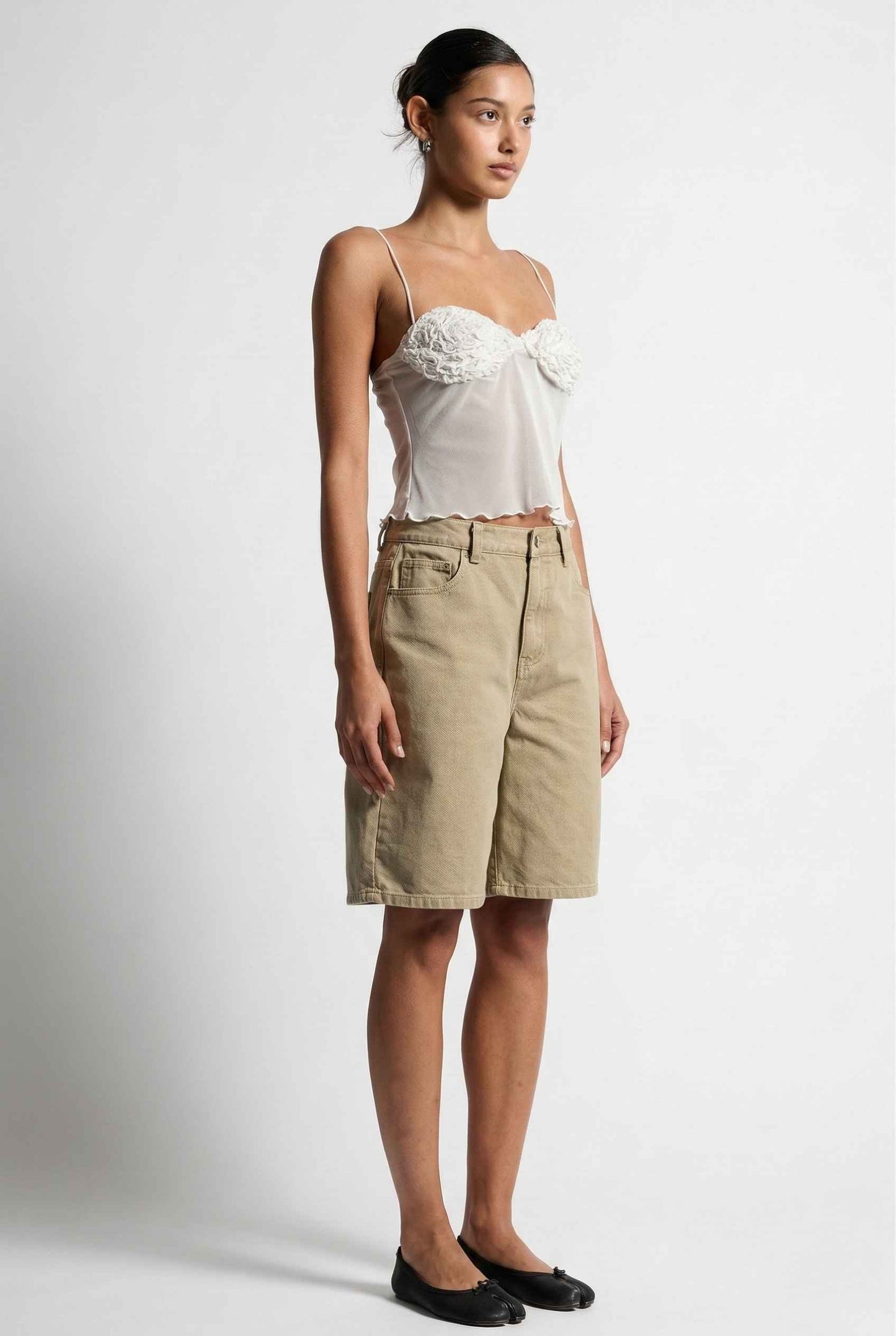 Woman wearing a Elara Top White Sheer Mesh Camisole with 3D Floral Cups and beige skirt on a white background