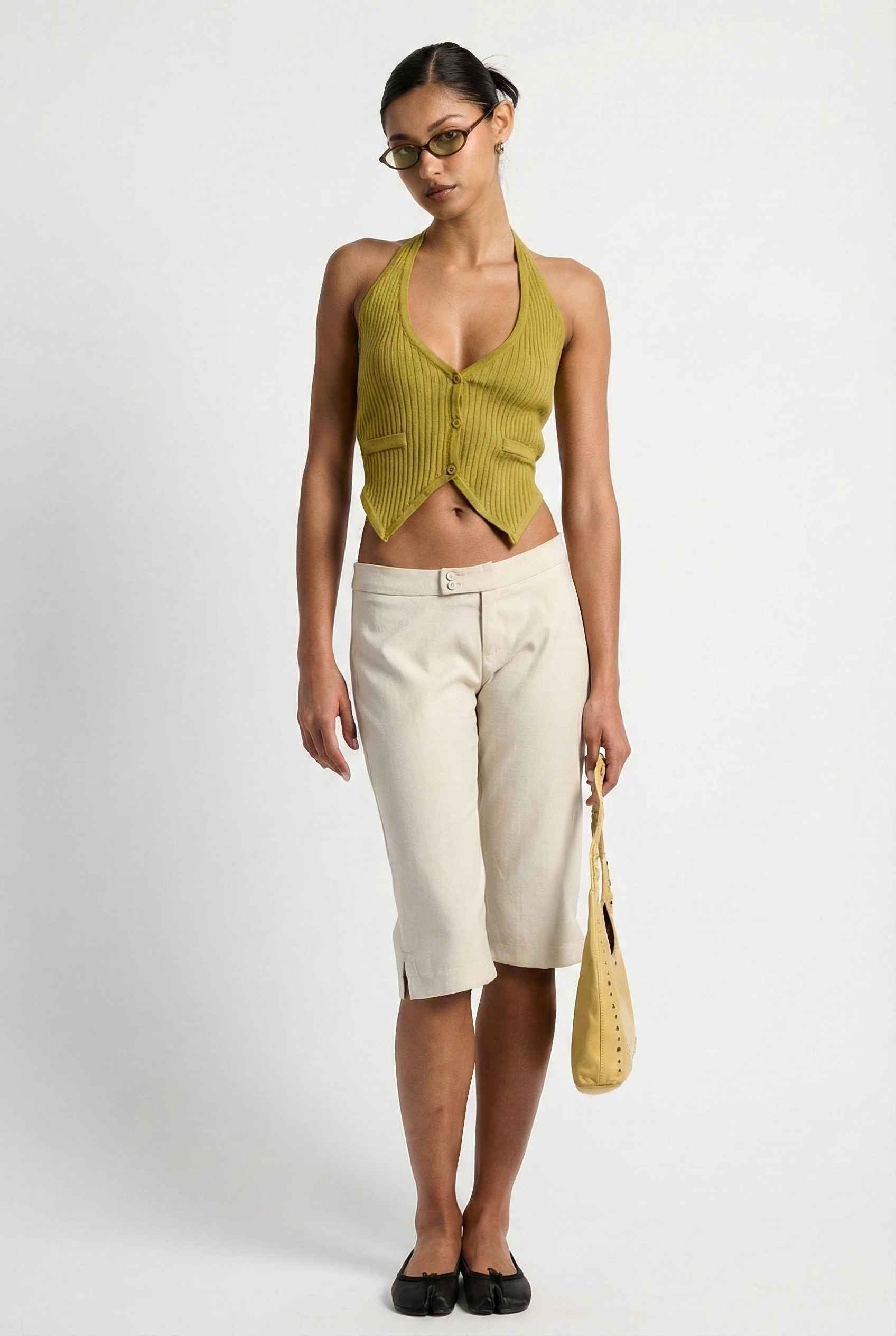 Model wearing Elise Shorts in Ivory Tailored Mid-Rise Bermuda Shorts with halter top and flats on plain background