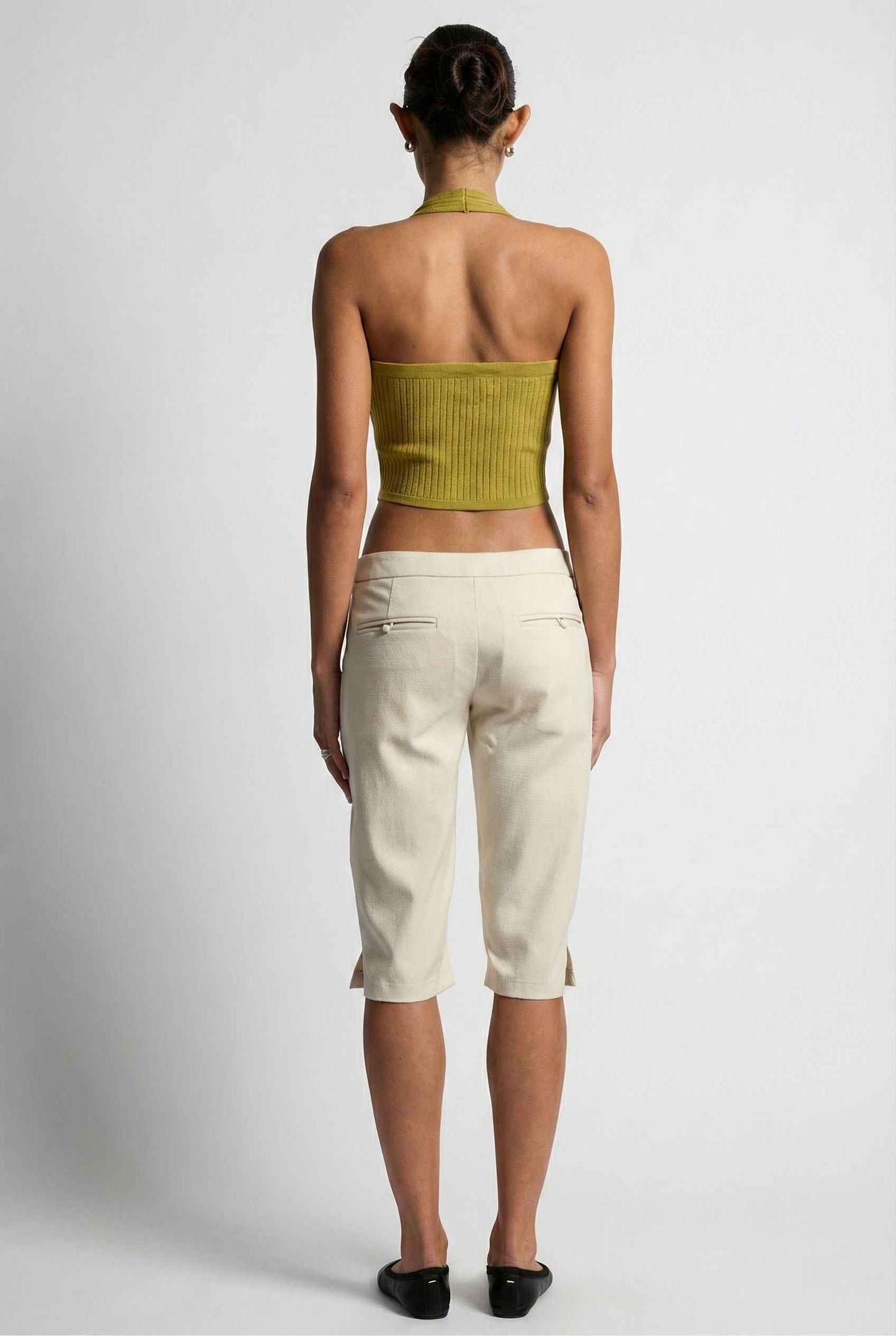 Model wearing Elise Shorts in Ivory Tailored Mid-Rise Bermuda Shorts with halter top and flats on plain background