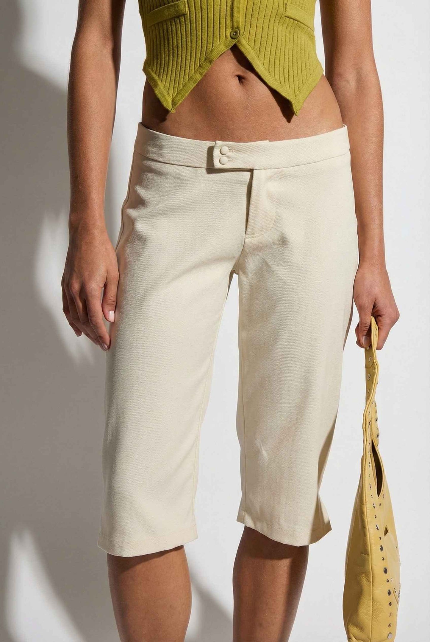 Model wearing Elise Shorts in Ivory Tailored Mid-Rise Bermuda Shorts with halter top on plain background