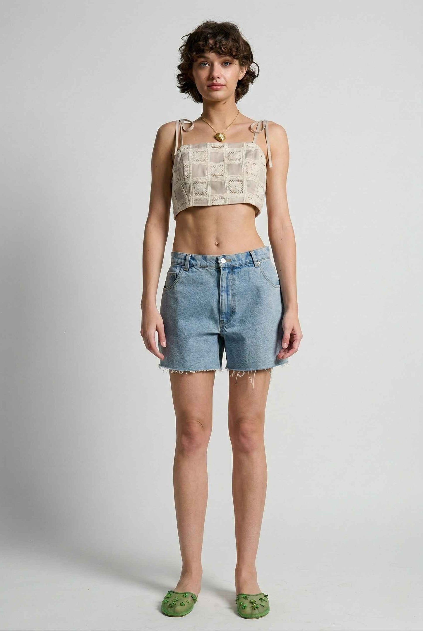 Model wearing Elodie Top in Natural Jacquard Square Neck Cami with Ribbon Tie Straps with denim shorts and slip on shoes on a plain background