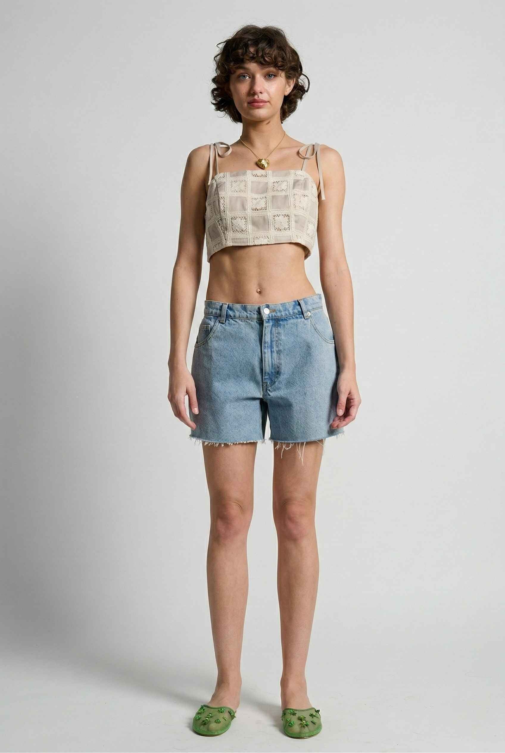 Model wearing Elodie Top in Natural Jacquard Square Neck Cami with Ribbon Tie Straps with denim shorts and slip on shoes on a plain background