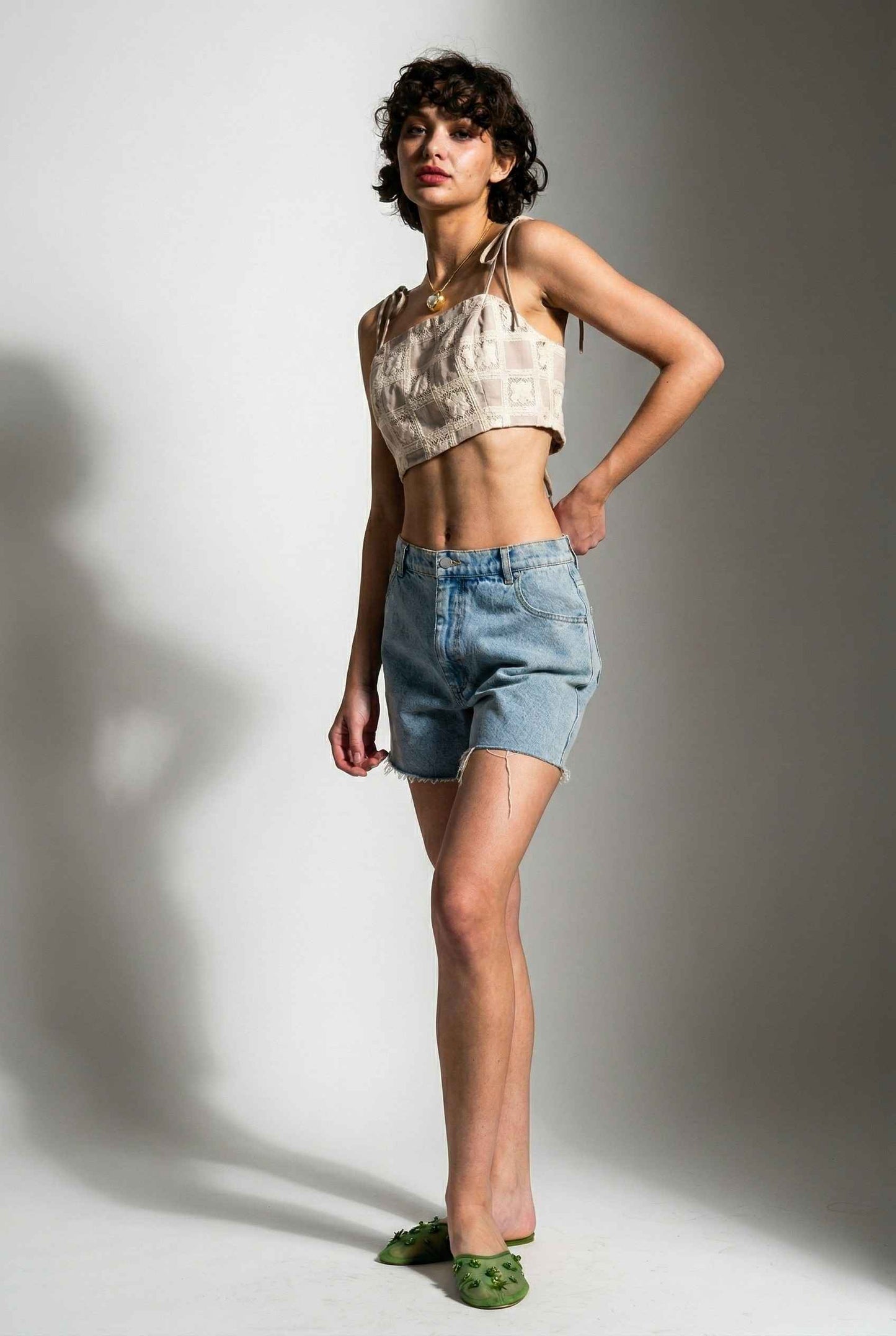 Model wearing Elodie Top in Natural Jacquard Square Neck Cami with Ribbon Tie Straps with denim shorts and slip on shoes on a plain background