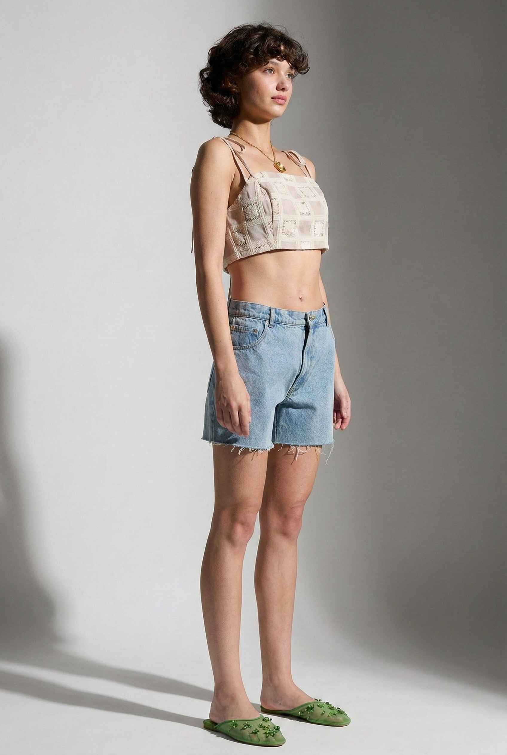 Model wearing Elodie Top in Natural Jacquard Square Neck Cami with Ribbon Tie Straps with denim shorts and slip on shoes on a plain background