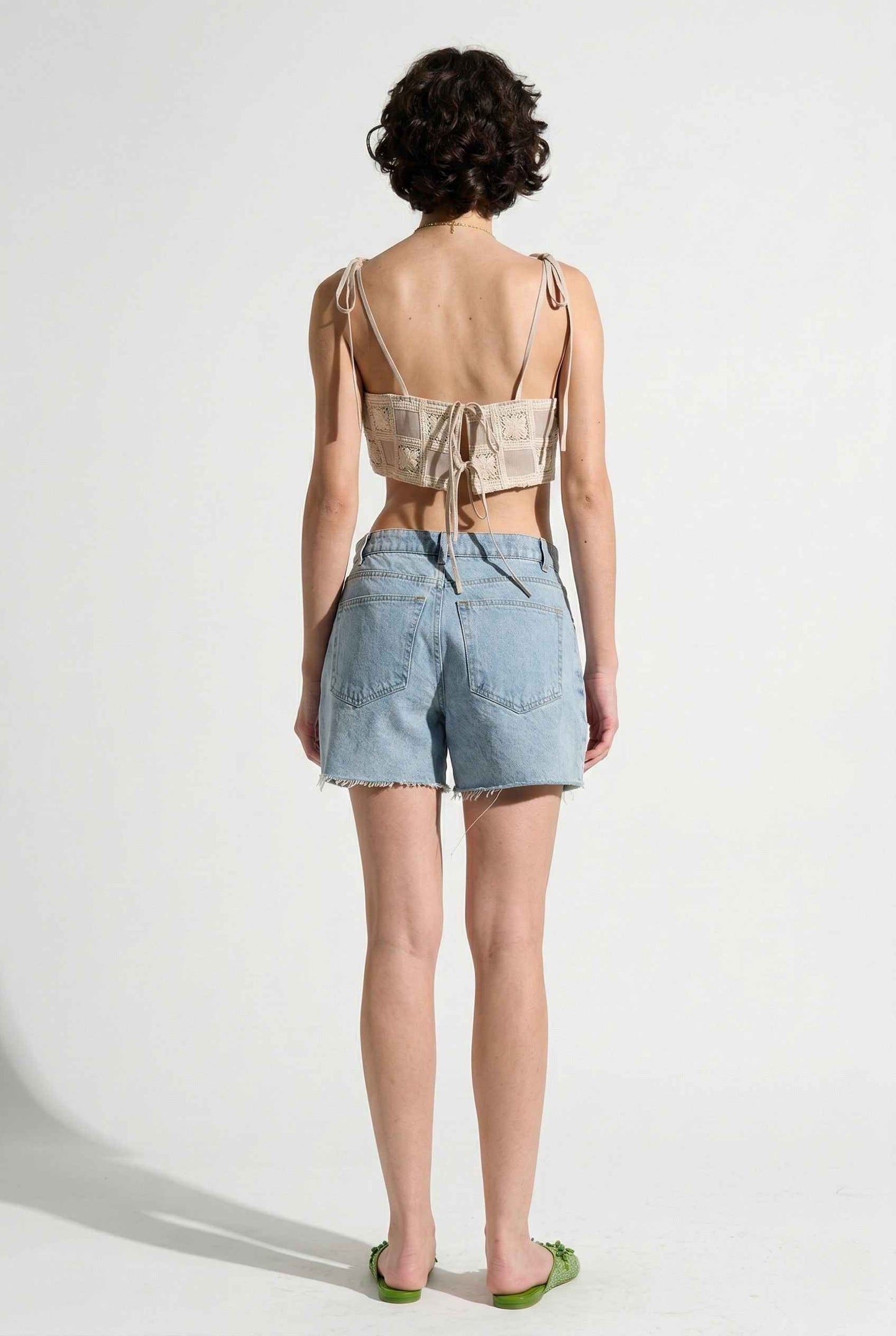 Model wearing Elodie Top in Natural Jacquard Square Neck Cami with Ribbon Tie Straps with denim shorts and slip on shoes on a plain background