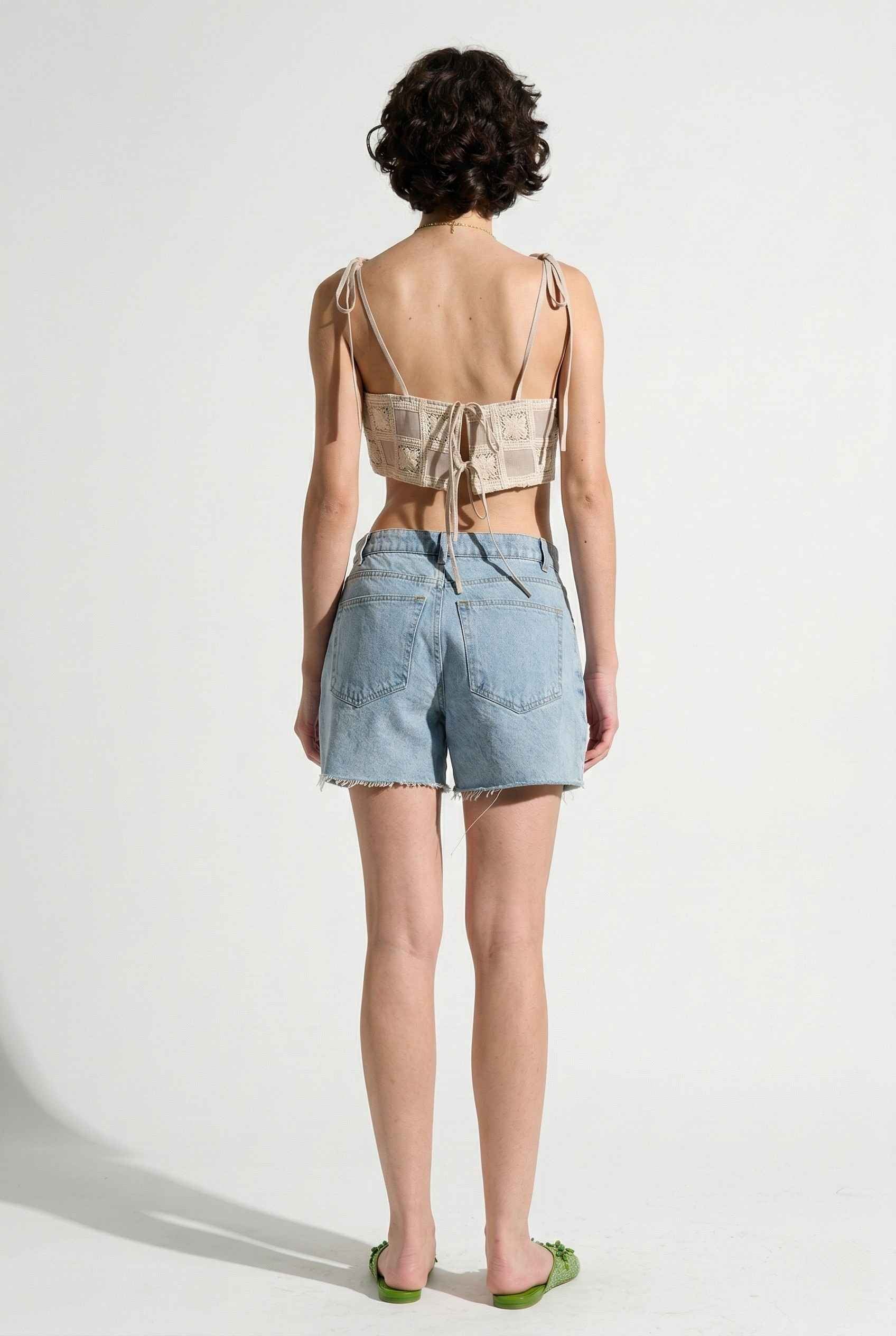 Model wearing Elodie Top in Natural Jacquard Square Neck Cami with Ribbon Tie Straps with denim shorts and slip on shoes on a plain background