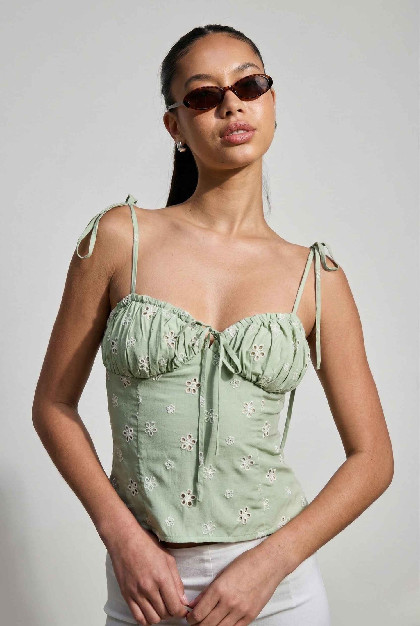 Woman wearing a Elodie Top Mint Floral Embroidered Tie-Strap Corset Top against a plain background