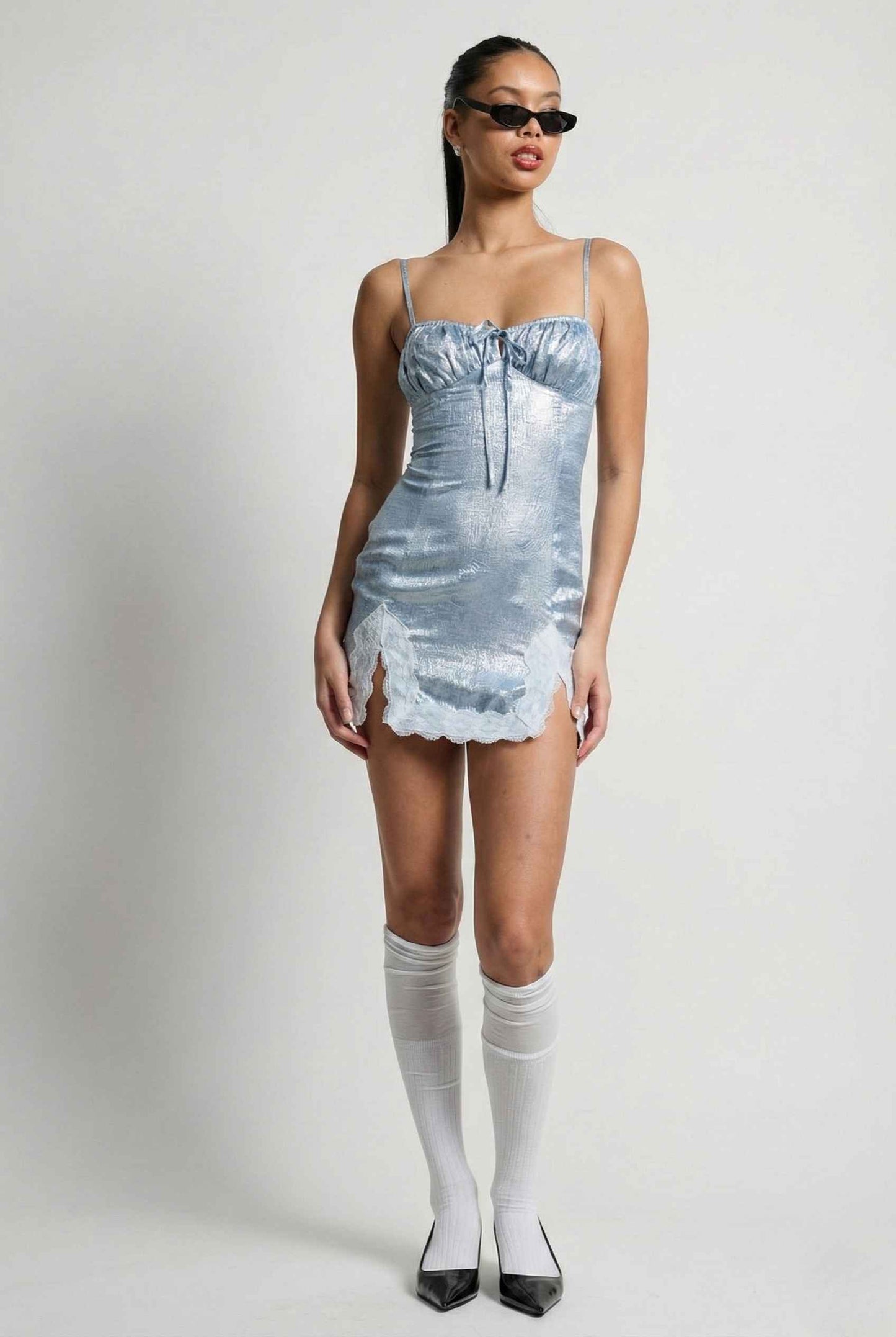 Woman wearing a Esme Mini Light Blue Satin Lace Hem Dress with a textured pattern on a plain background