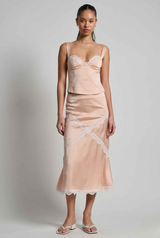 Woman wearing a Freya Skirt Blush Pink Satin Midi Skirt with White Lace Detail with lace details on a plain background