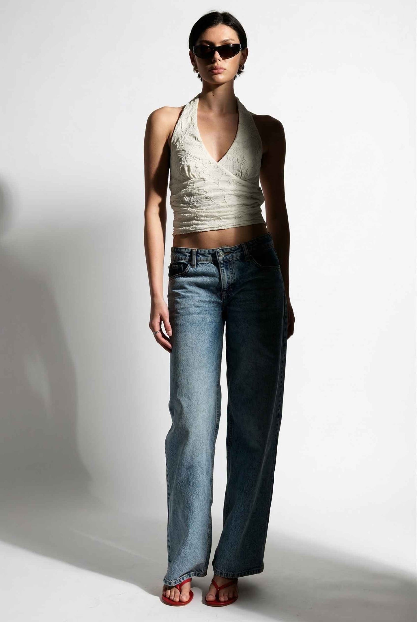 Woman wearing a Freya Top Ivory Floral Lace Wrap Halter Crop posing.