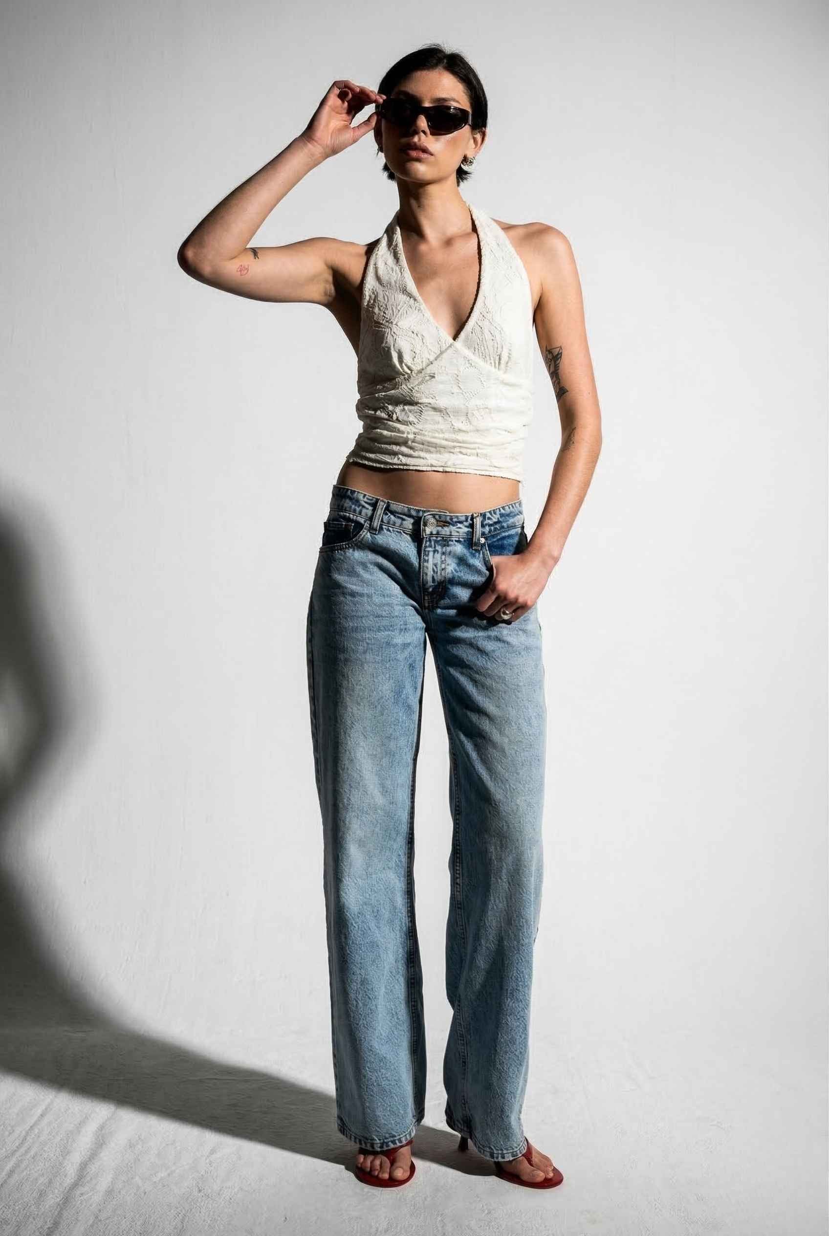 Woman wearing a Freya Top Ivory Floral Lace Wrap Halter Crop posing.