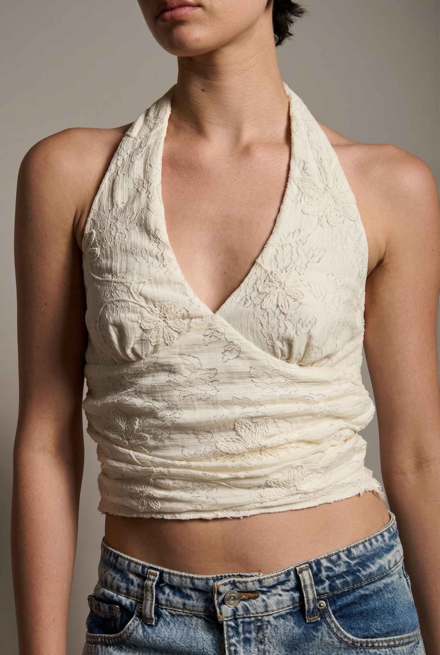 Woman wearing a Freya Top Ivory Floral Lace Wrap Halter Crop close up.
