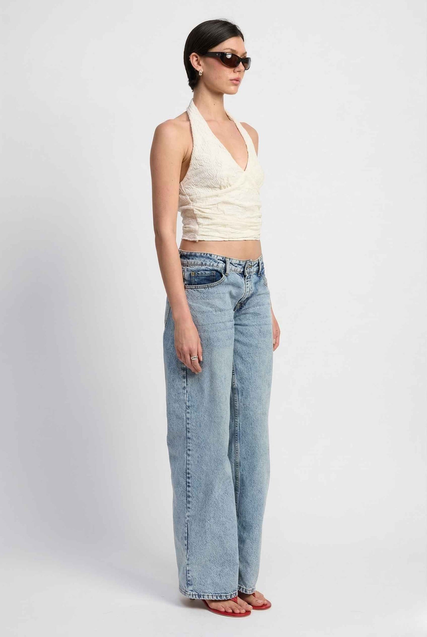 Woman wearing a Freya Top Ivory Floral Lace Wrap Halter Crop side view.