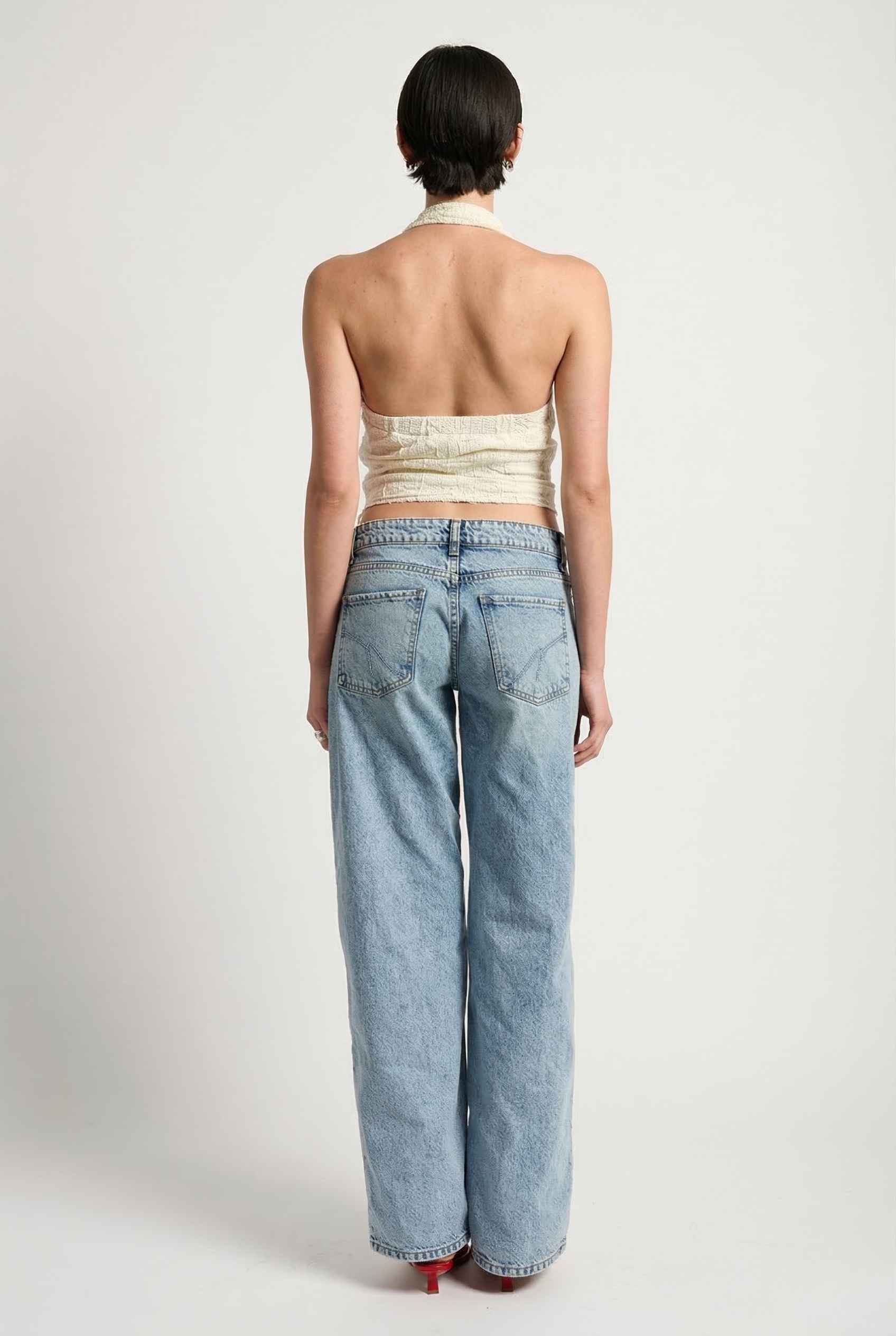 Woman wearing a Freya Top Ivory Floral Lace Wrap Halter Crop back view.