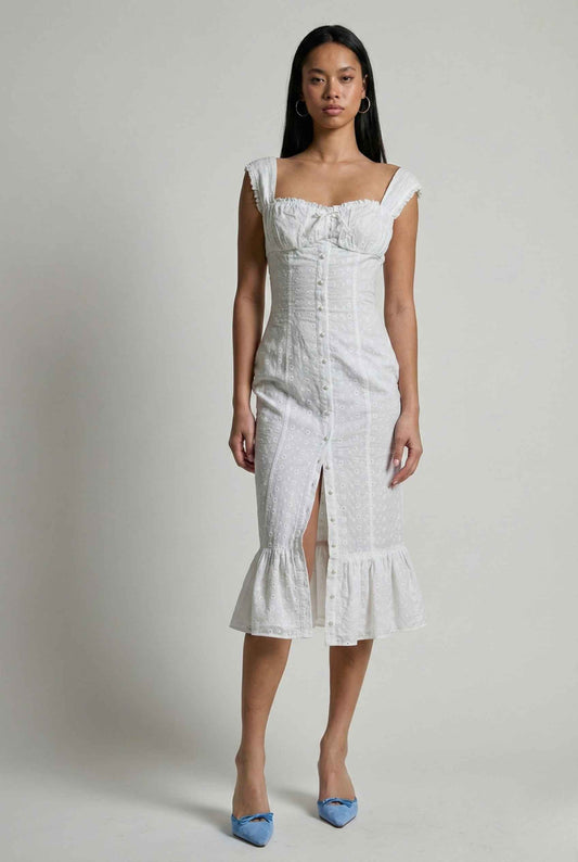 Woman wearing a Genevieve Midi White Eyelet Cotton Button Dress with ruffled details on a plain background