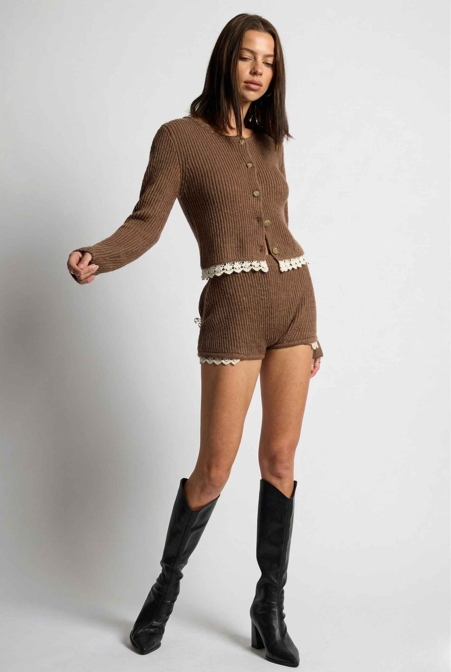 Woman wearing a Hazel Shorts Brown Ribbed Knit Micro Shorts with Lace Trim with black knee-high boots on a white background