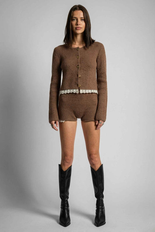 Woman wearing a brown cardigan and Hazel Shorts Brown Ribbed Knit Micro Shorts with Lace Trim with black knee-high boots on a gray background