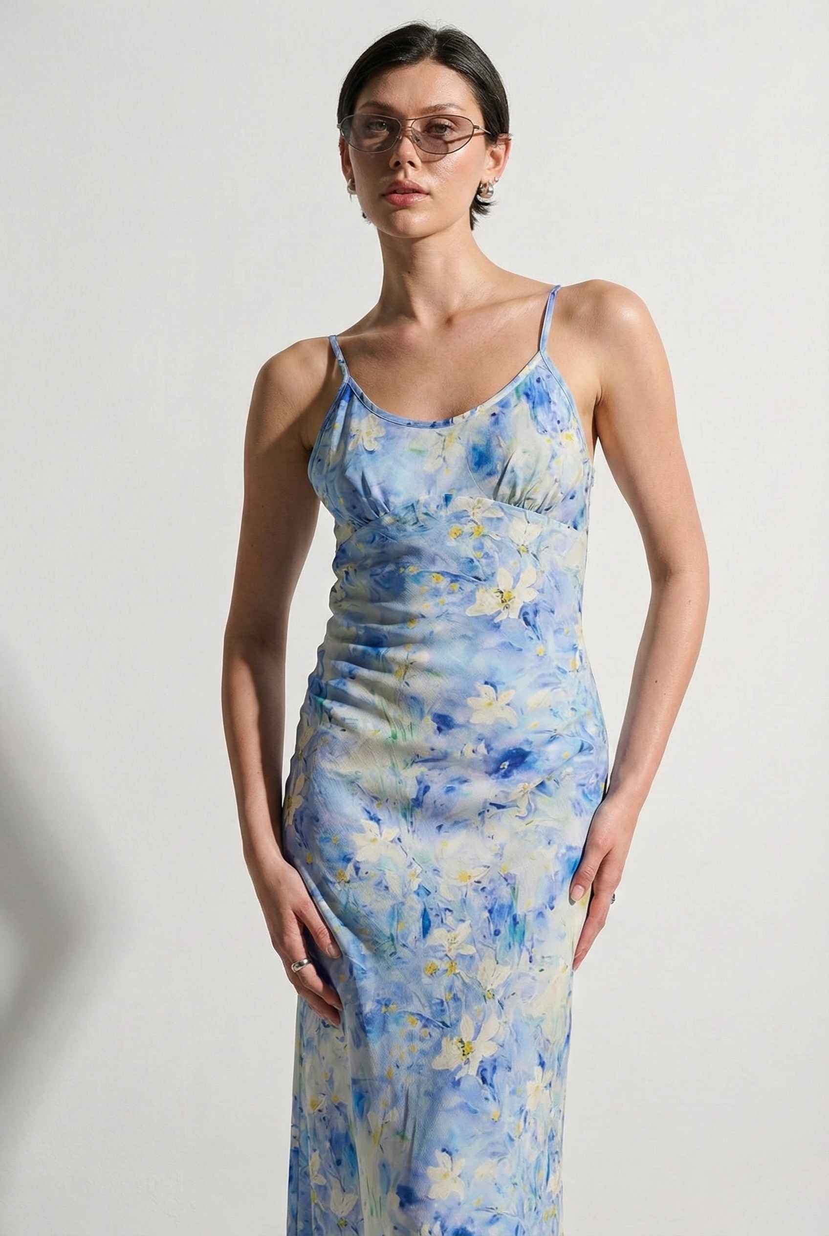Woman wearing a Iris Midi Light Blue Floral Satin Slip Dress against a plain background