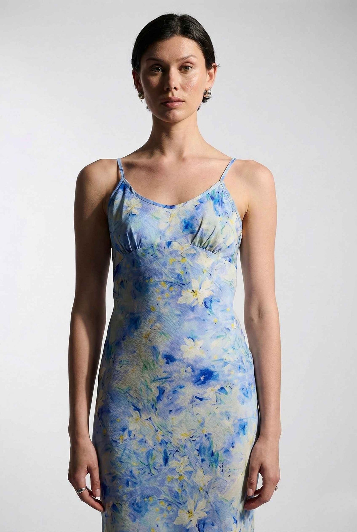 Woman wearing a Iris Midi Light Blue Floral Satin Slip Dress against a plain background