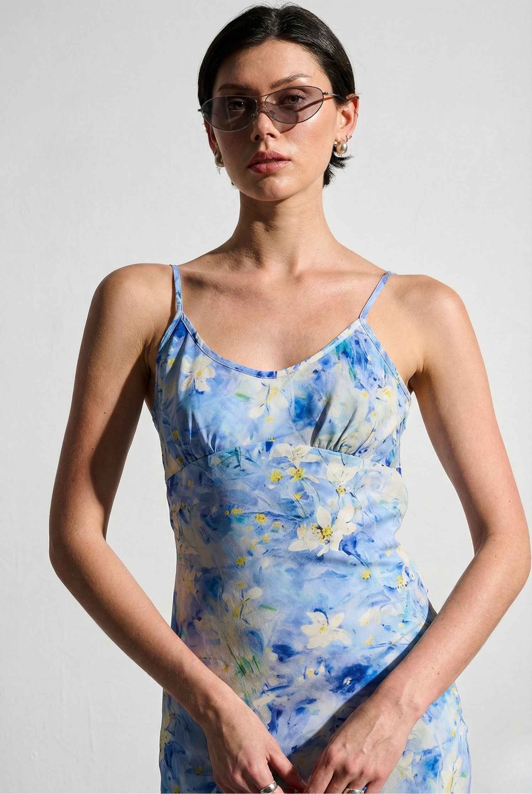 Woman wearing a Iris Midi Light Blue Floral Satin Slip Dress against a plain background