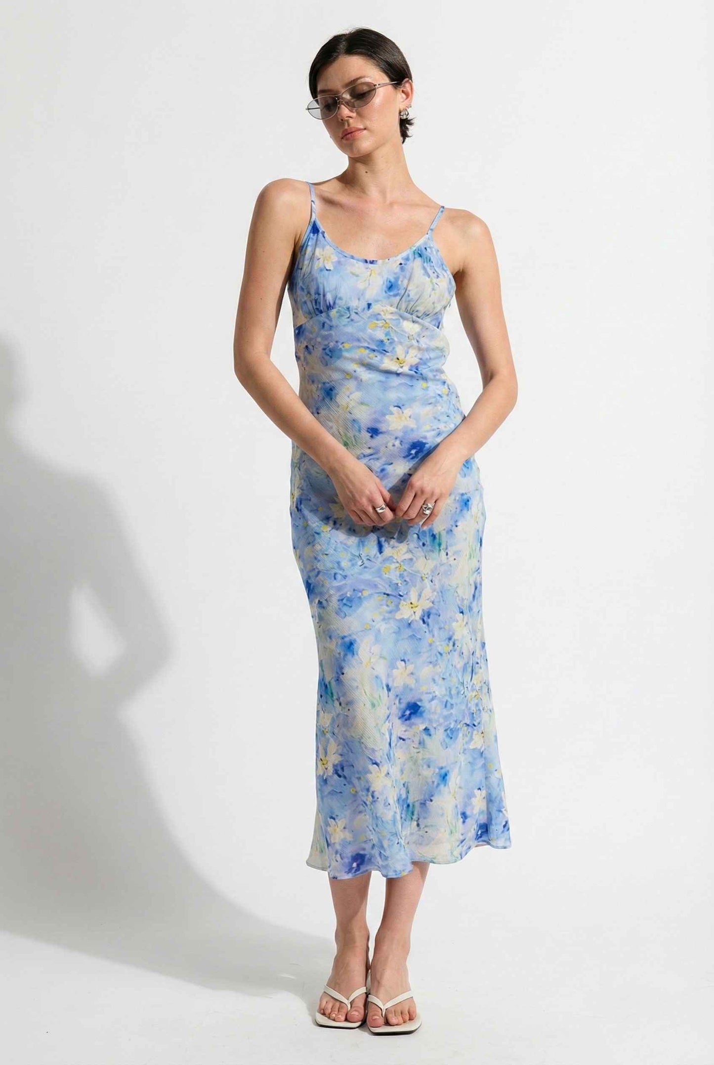 Woman wearing a Iris Midi Light Blue Floral Satin Slip Dress against a white background